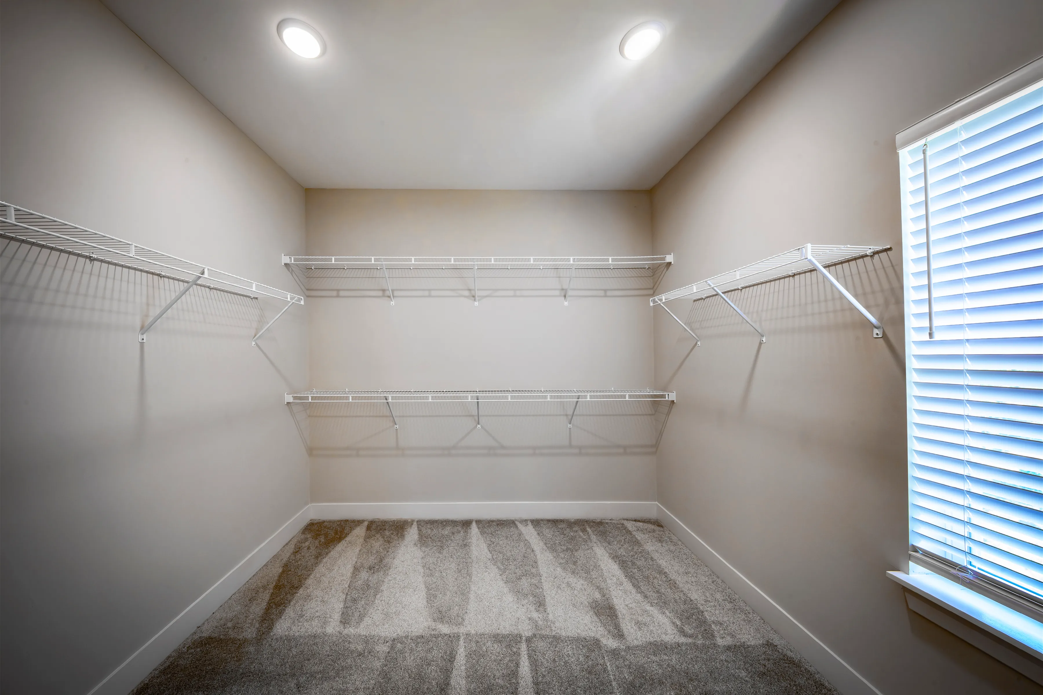 Spacious walk-in closet with sleek wire shelving and natural light, perfect for organizing your wardrobe.