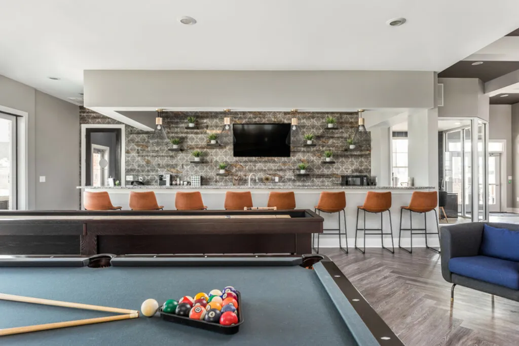 Modern game room with a sleek pool table, stylish bar seating, and elegant decor, ideal for entertainment and relaxation.