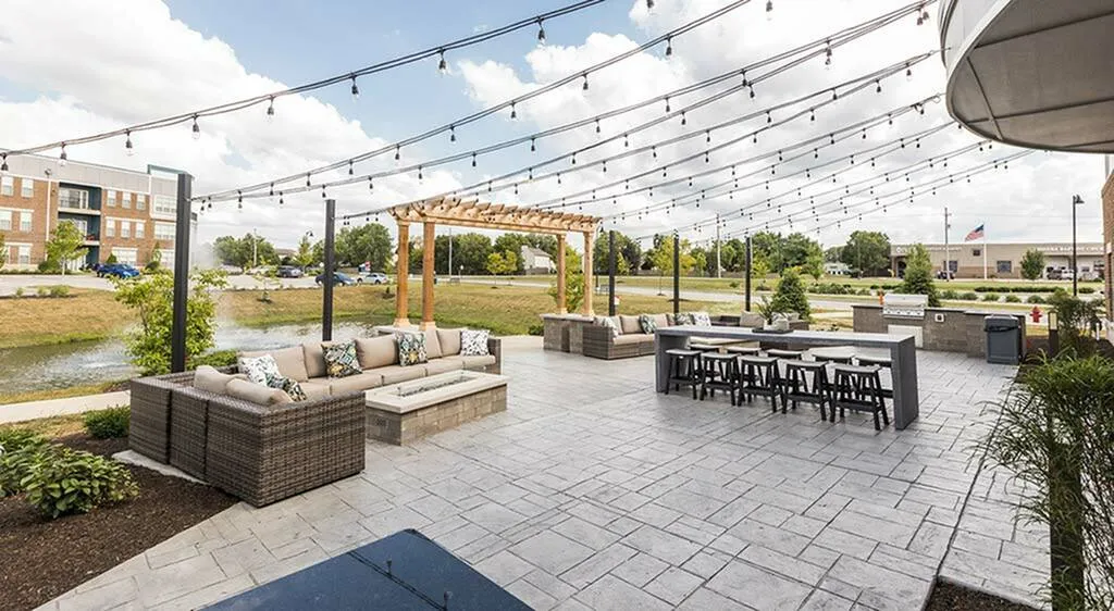 Charming outdoor patio with stylish seating area, string lights, and pergola overlooking scenic water views.