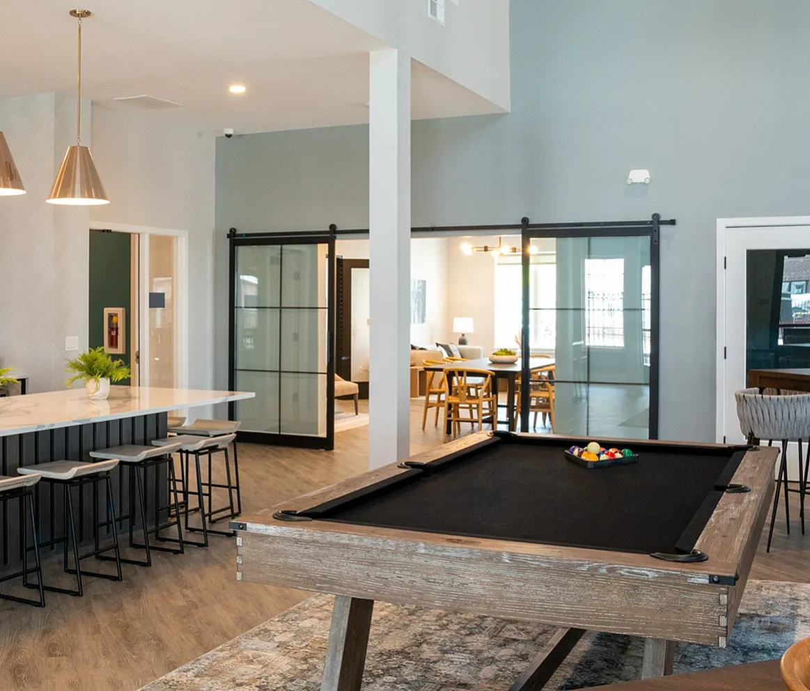Luxurious open-concept apartment interior featuring a stylish kitchen island with pendant lighting, chic bar stools, a cozy dining area, and a modern pool table.