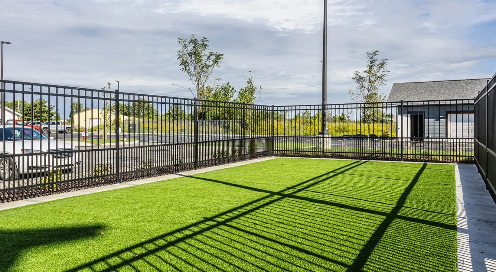 Inviting fenced outdoor area with vibrant green grass, perfect for relaxation or play under the open sky.