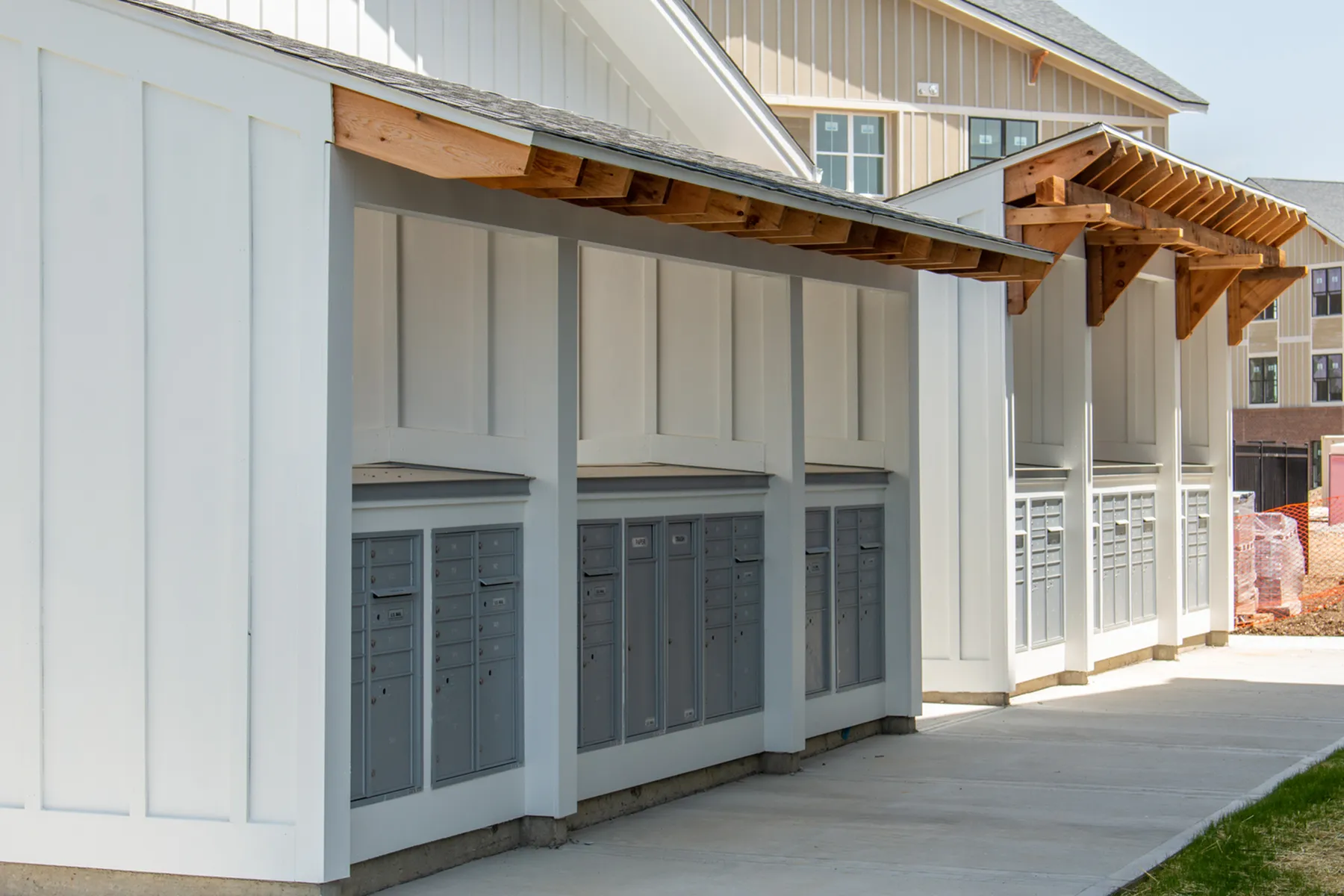 Charming community mail station with stylish wooden accents and secure mailboxes, set against a pristine residential backdrop.