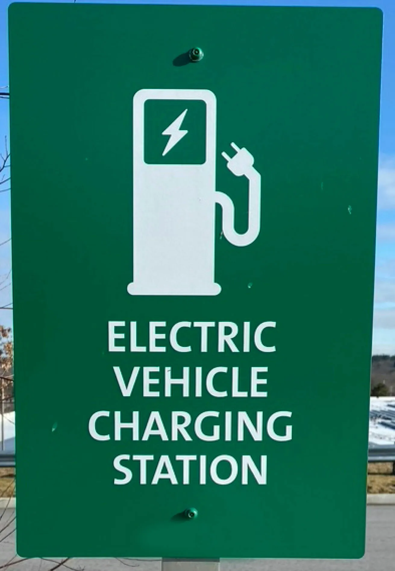 Green sign for electric vehicle charging station featuring a plug icon with a lightning bolt, indicating a convenient spot for eco-friendly car refueling.