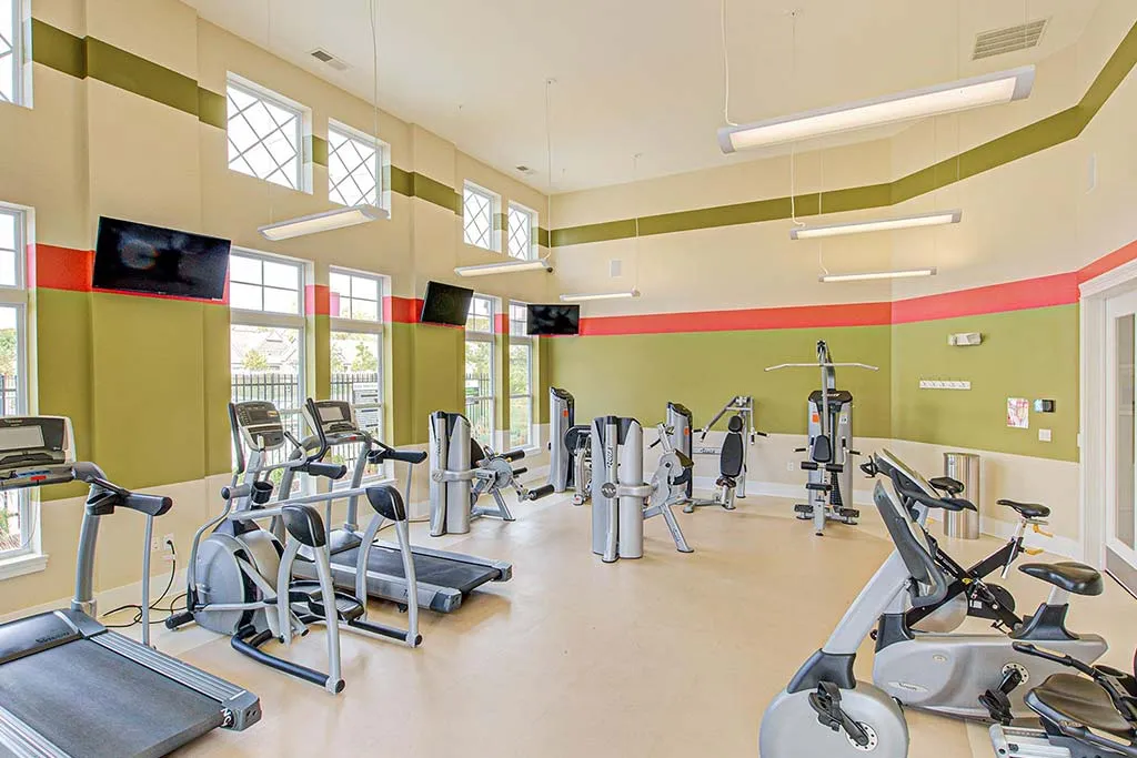 Bright fitness center with modern equipment, including treadmills, stationary bikes, and weight-lifting equipment.