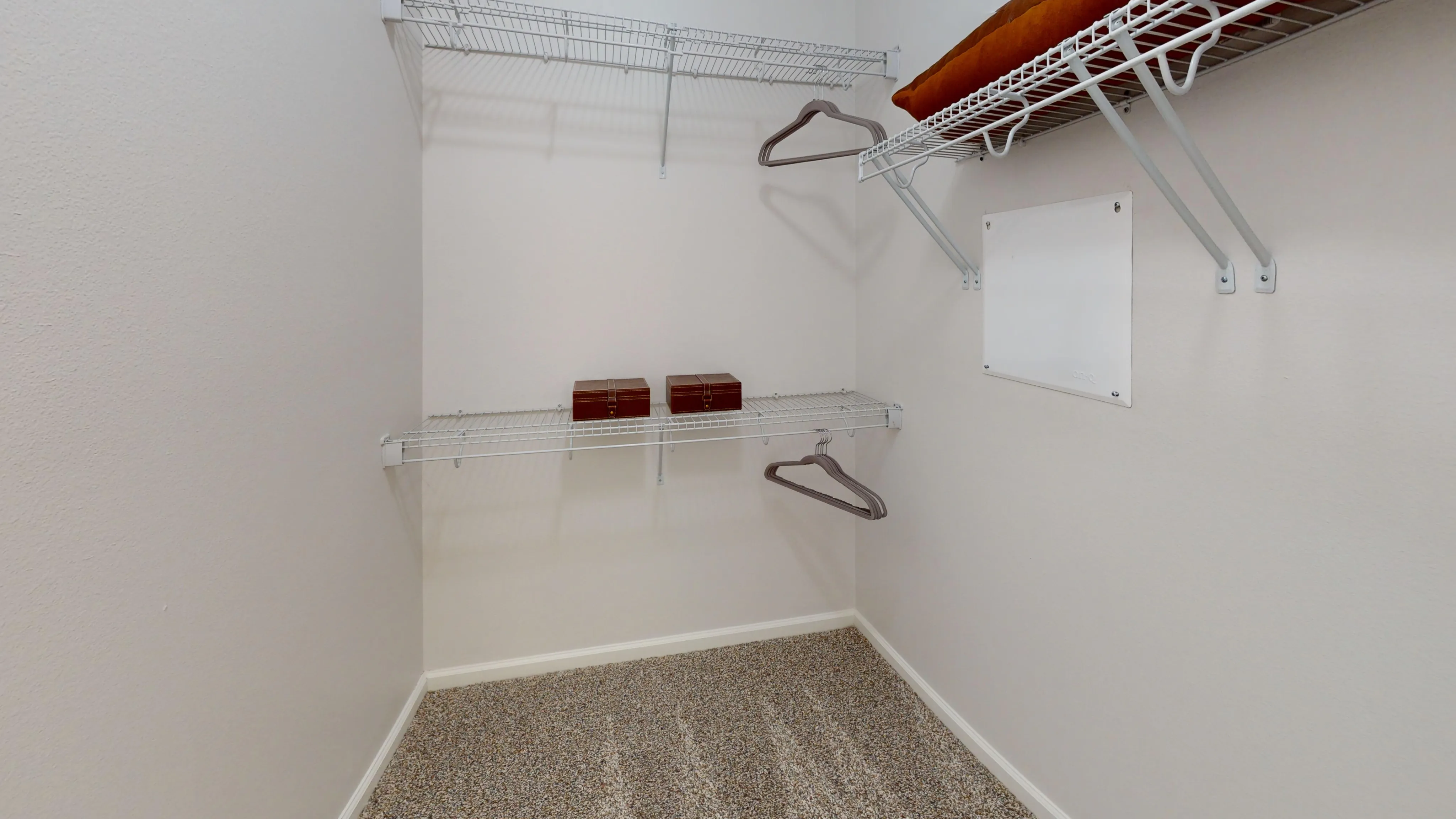 Spacious walk-in closet with white wire shelving, plush carpet, and ample storage space.