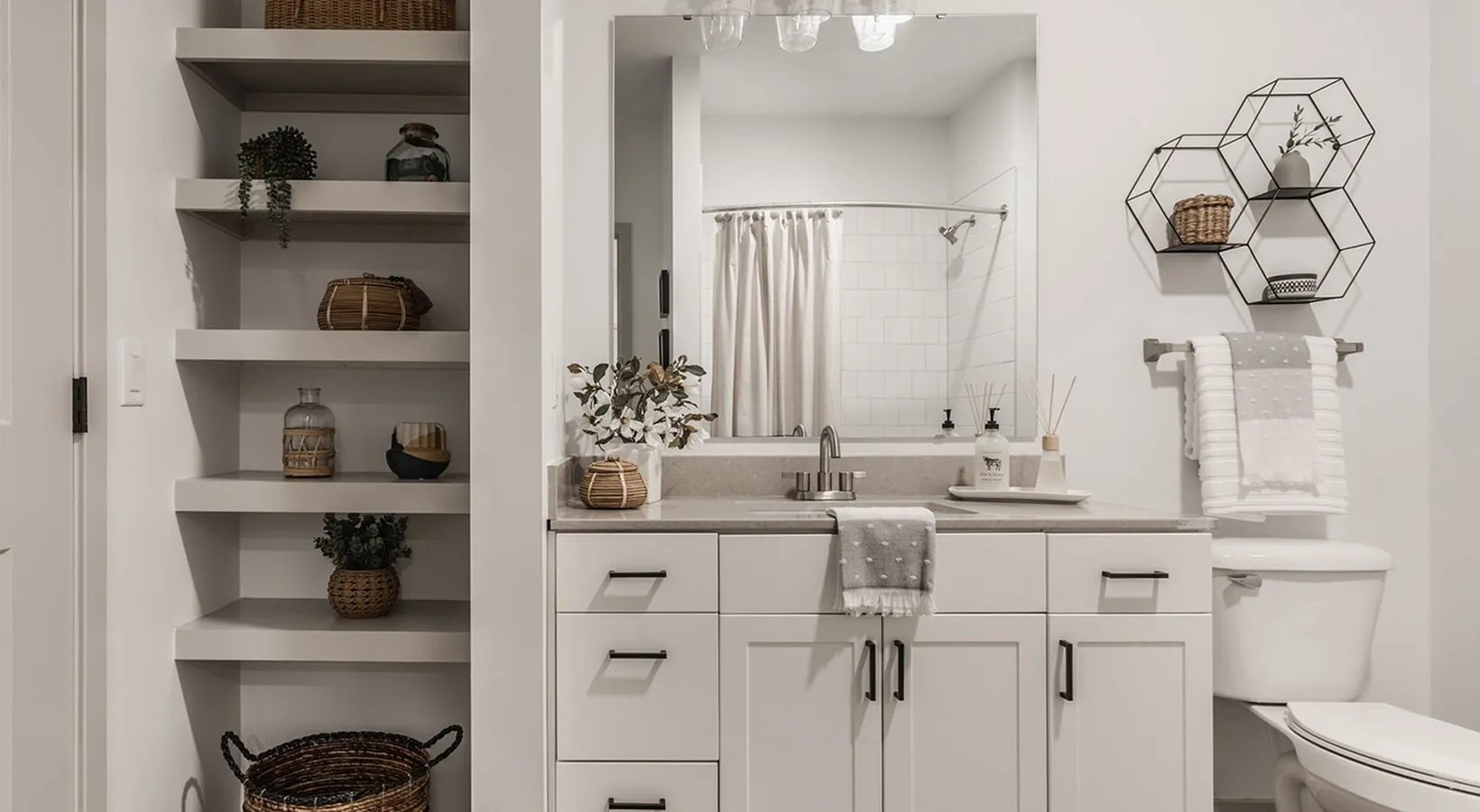 Modern bathroom with elegant shelving, sleek countertop, and stylish decor, showcasing minimalist design and bright lighting.