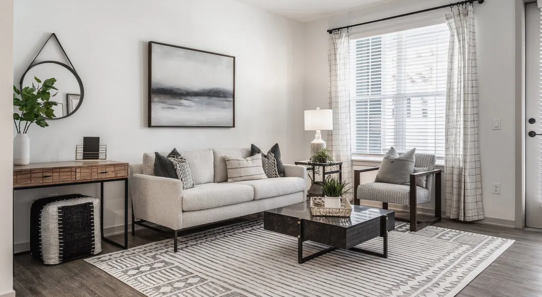 Modern and elegant living room with a cozy beige sofa, chic decor, and abundant natural light through large windows.