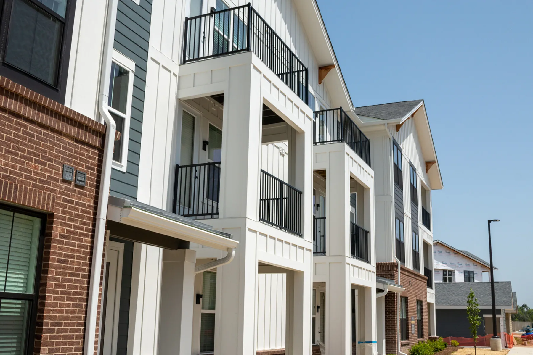 Modern apartment complex with stylish balconies and elegant facade under a clear blue sky.
