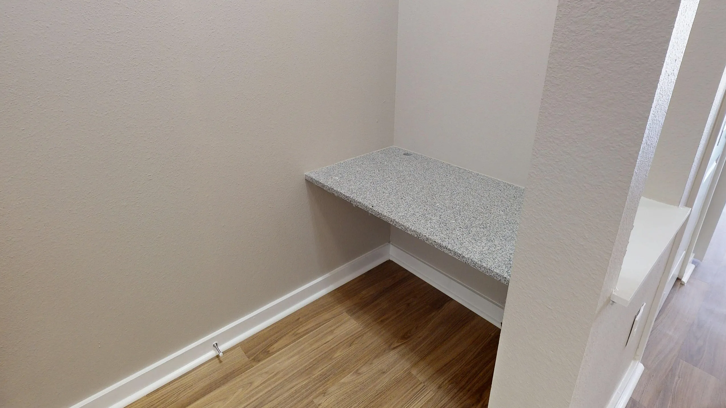 Chic corner office nook with a sleek granite desk and stylish hardwood floors, perfect for maximizing space and style in your home.