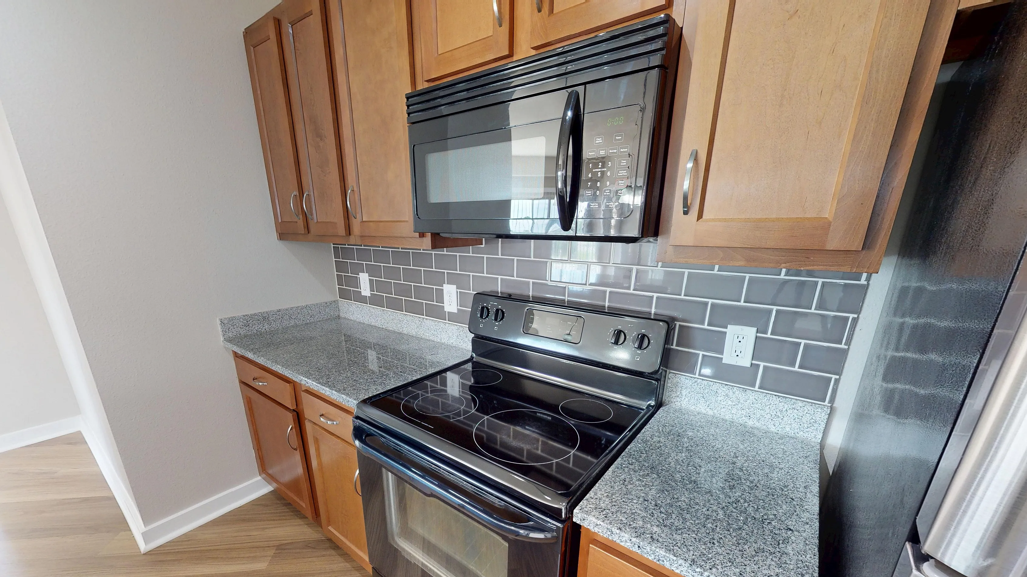 Modern kitchen featuring elegant wooden cabinetry, sleek black appliances, and gleaming granite countertops.