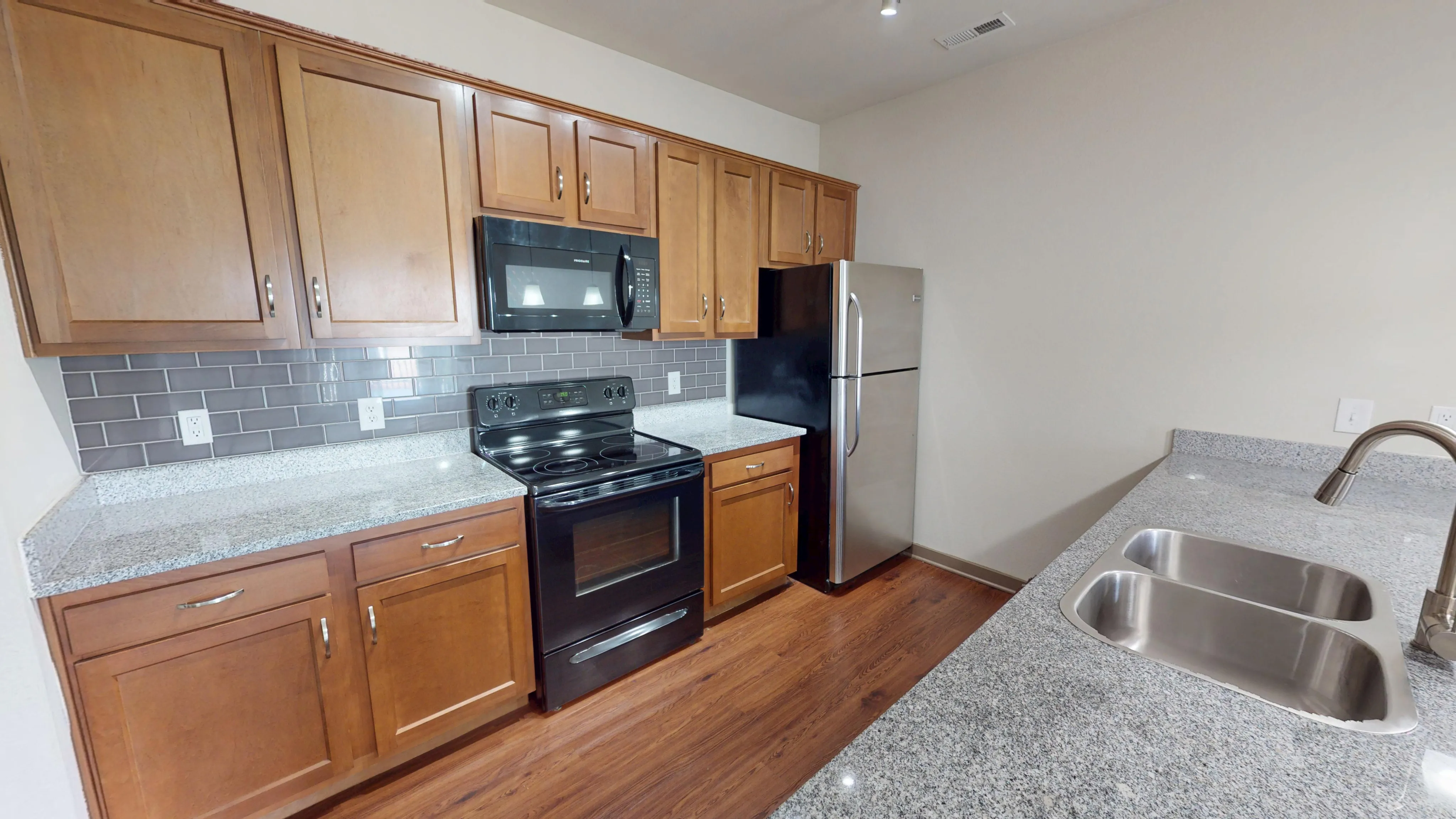 Modern kitchen with sleek granite countertops, stainless steel appliances, warm wooden cabinetry, and a stylish tile backsplash.