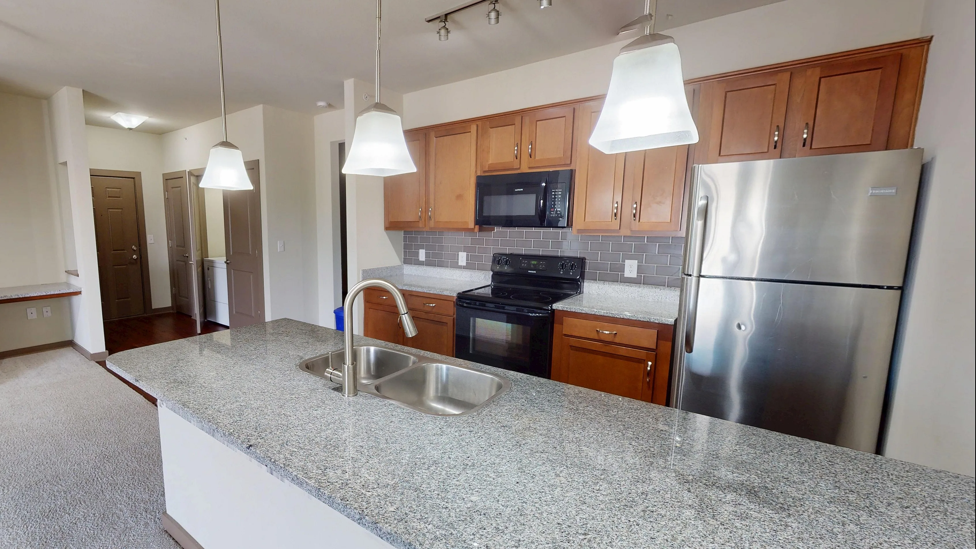 Modern kitchen with elegant granite countertops, stainless steel appliances, and ambient pendant lighting, perfect for culinary enthusiasts.