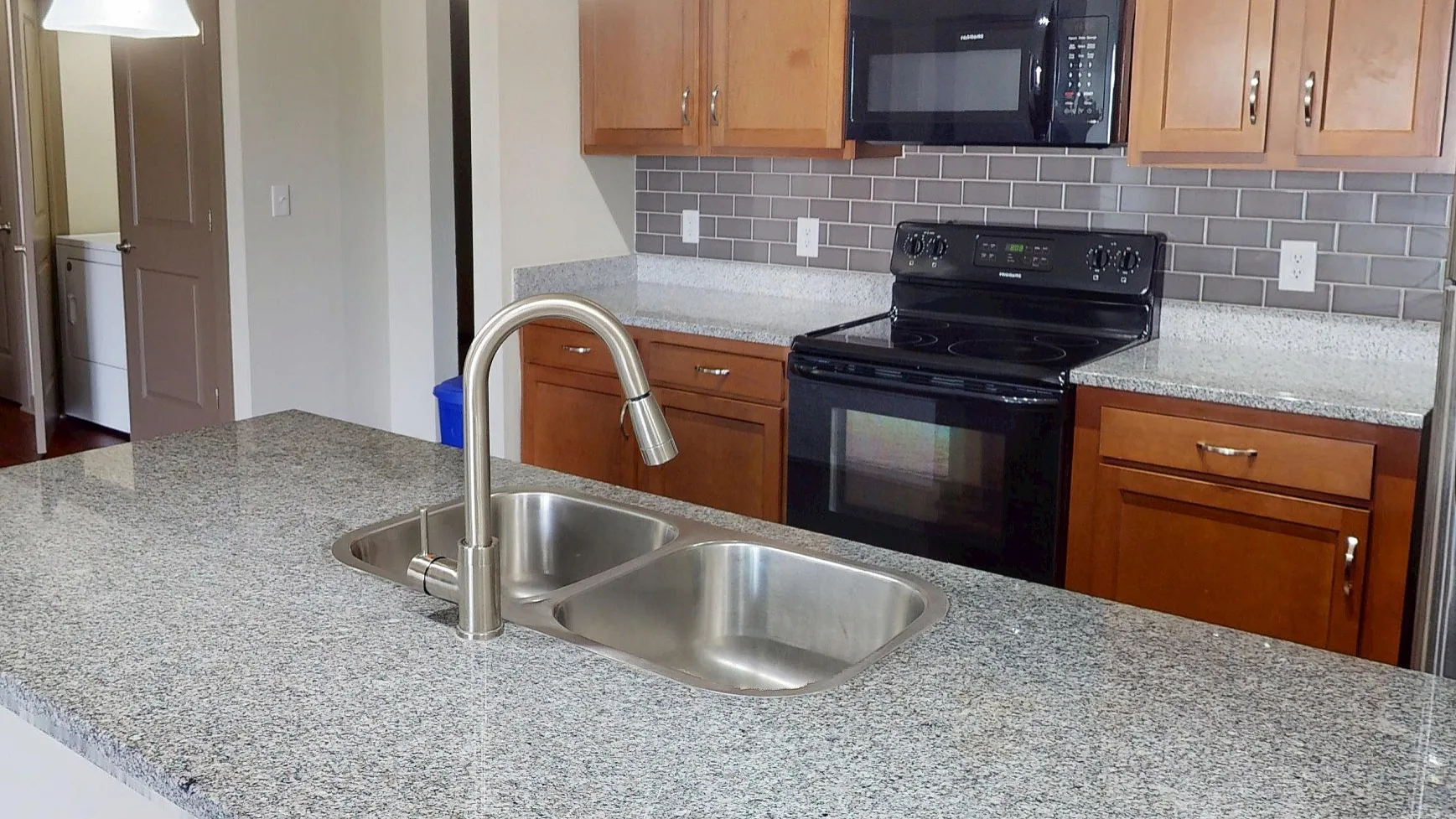 Modern open-concept kitchen with sleek granite countertops, stainless steel appliances, and elegant pendant lighting.