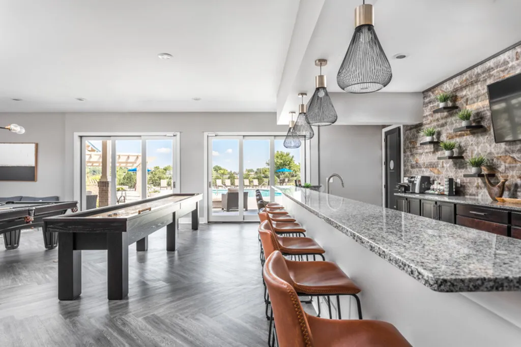 Luxurious entertainment lounge with chic granite bar, stylish lighting, and scenic outdoor view.