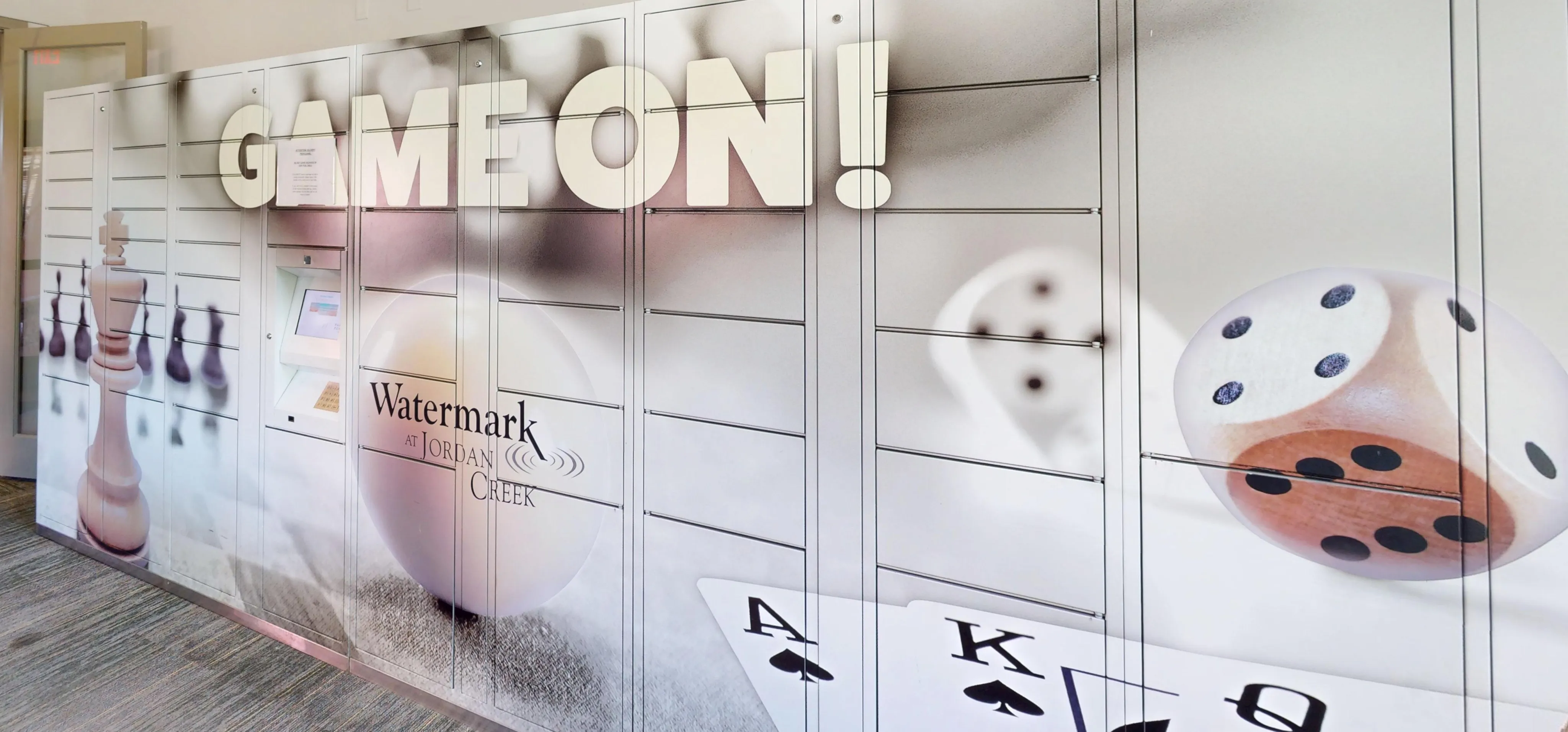 Dynamic wall mural with game-themed graphics including chess pieces, a die, and playing cards at Watermark at Jordan Creek.