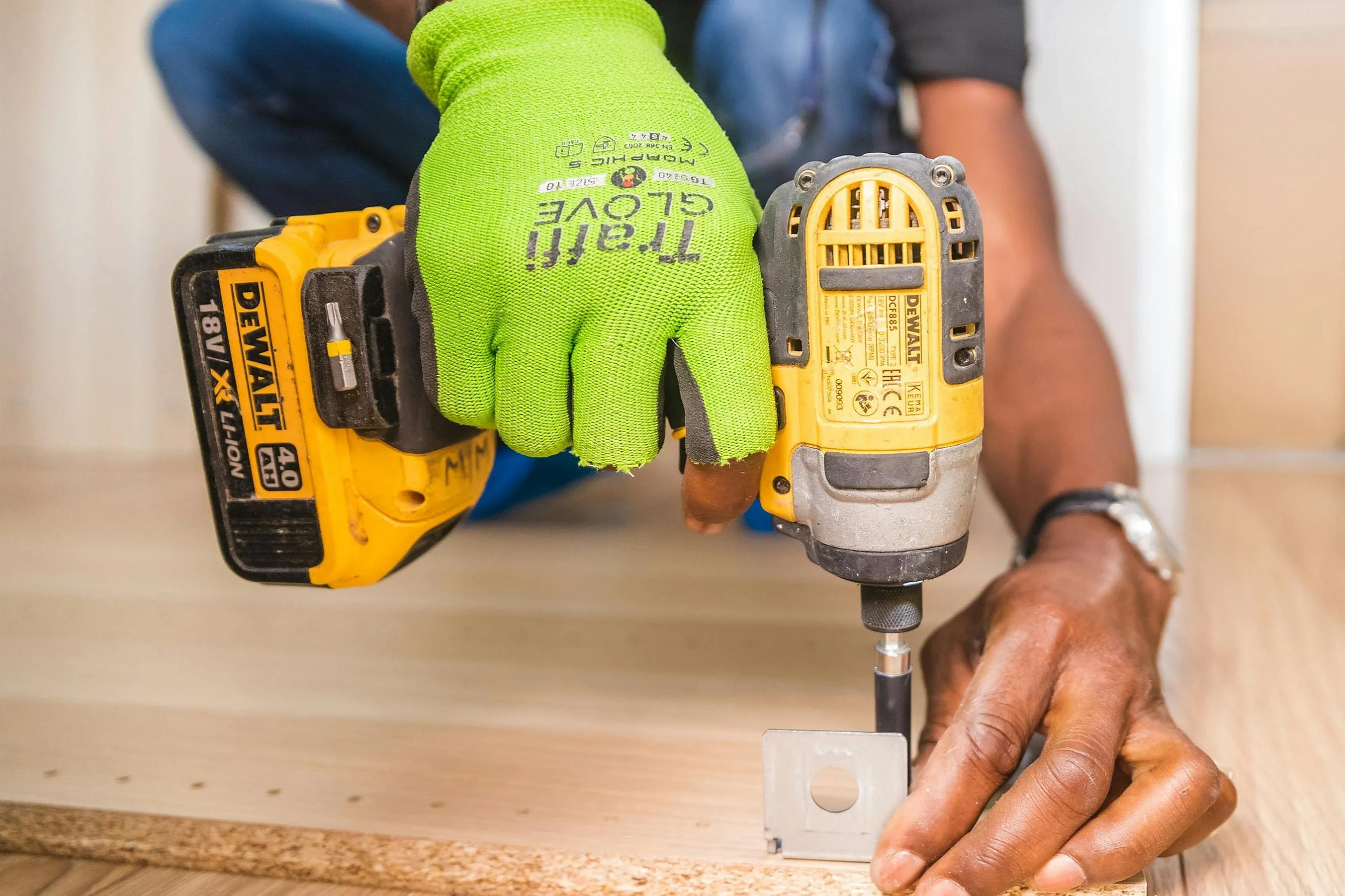 Close-up of a skilled worker using a power drill on a polished wooden floor, showcasing precision and craftsmanship in construction.