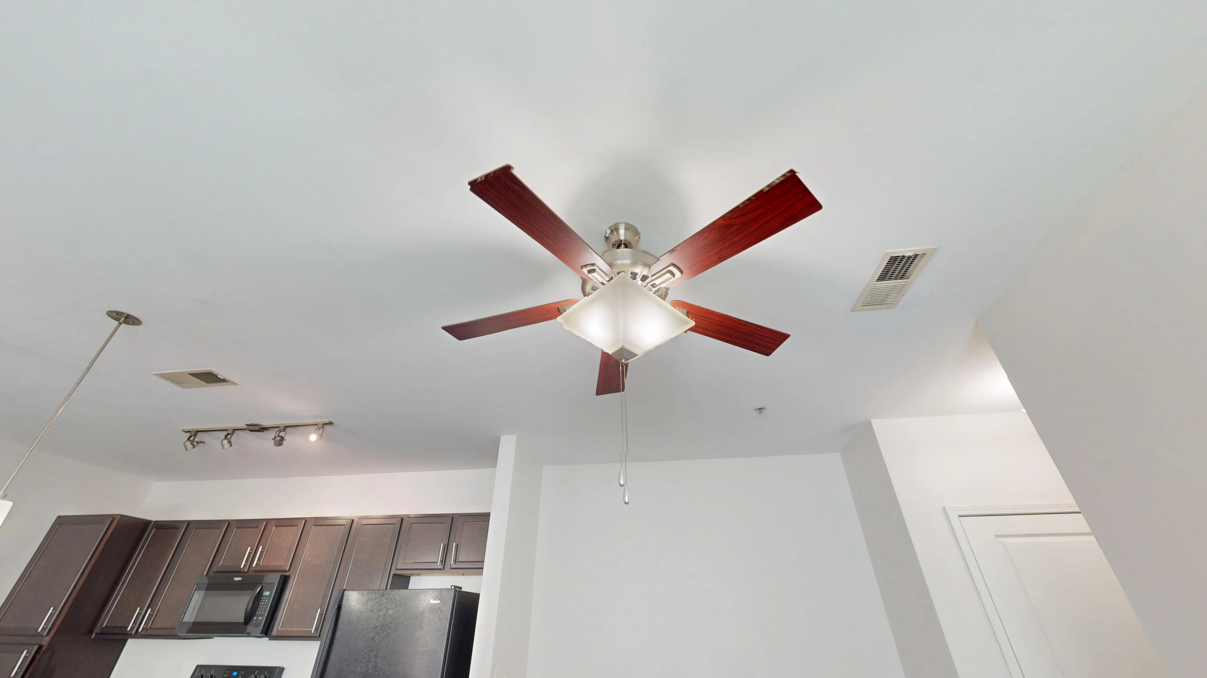 Modern apartment kitchen with sleek dark cabinets and elegant ceiling fan lighting.