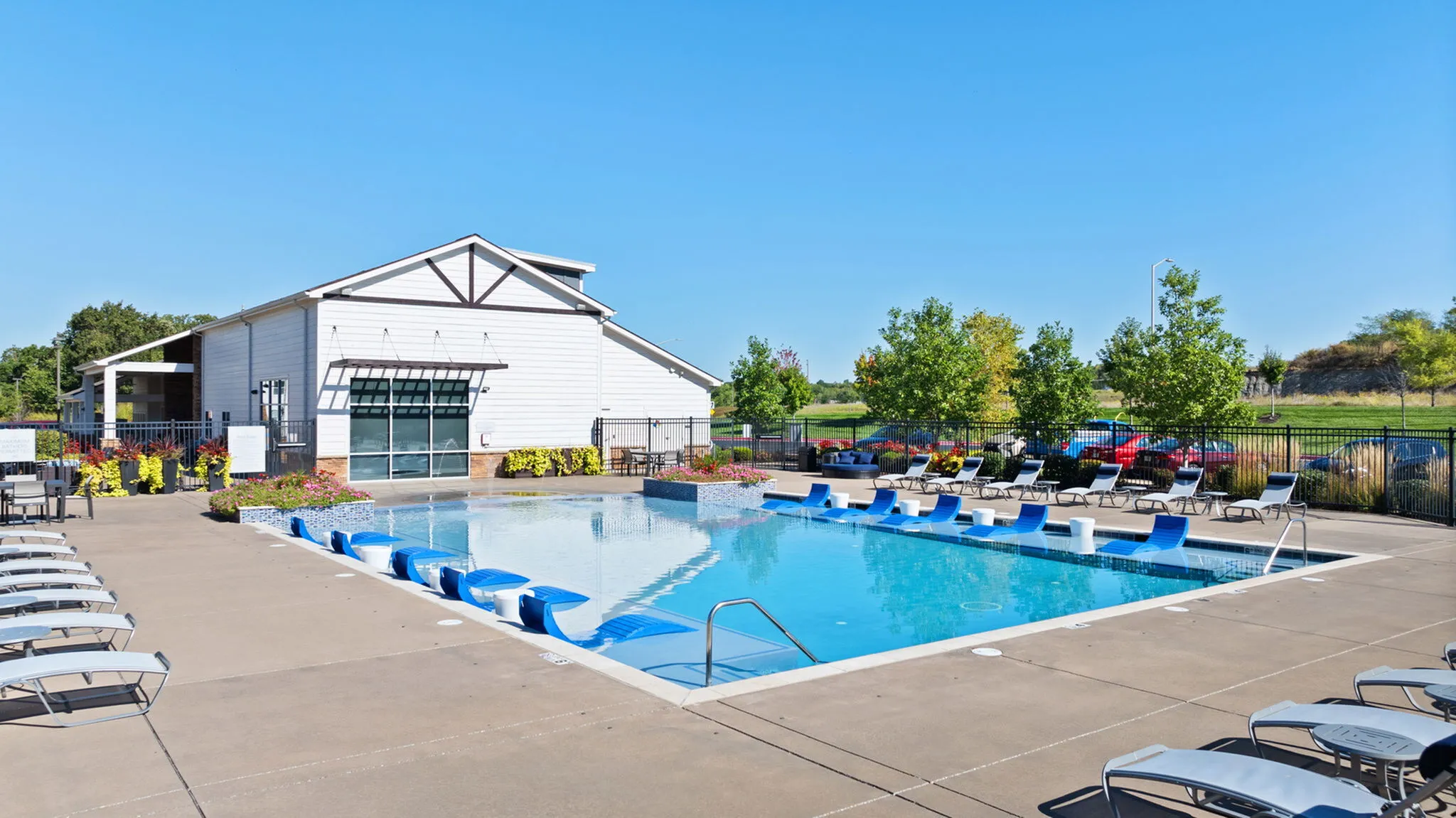 Inviting outdoor swimming pool with modern lounge chairs and vibrant landscaping, perfect for relaxation and leisure.