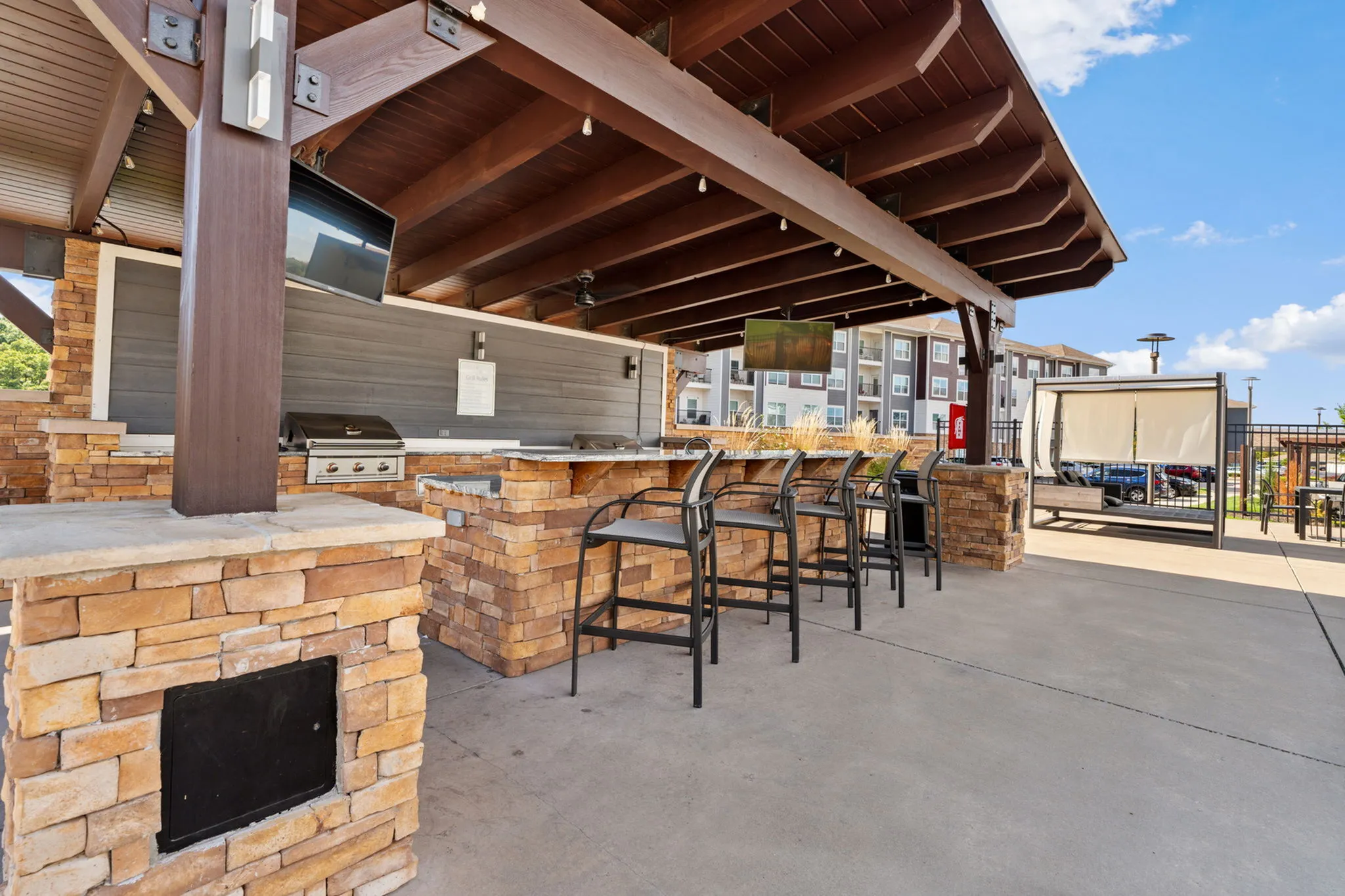 Chic outdoor BBQ area with stone countertops and bar seating, perfect for entertaining and relaxation.