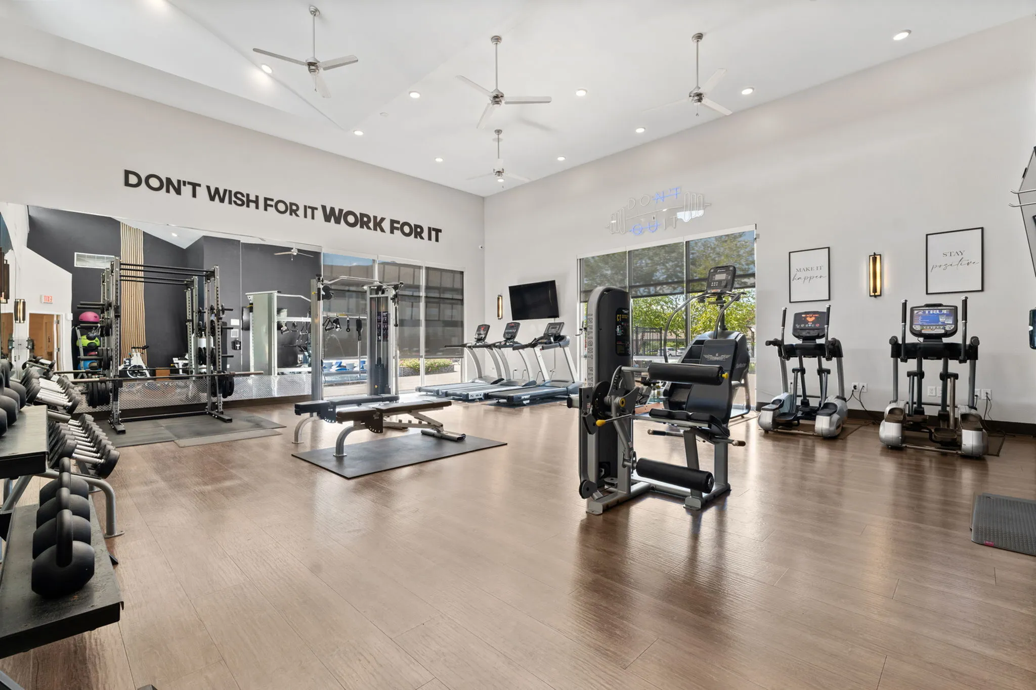 Bright and modern gym featuring state-of-the-art fitness equipment, motivational quotes, and large windows offering natural light.
