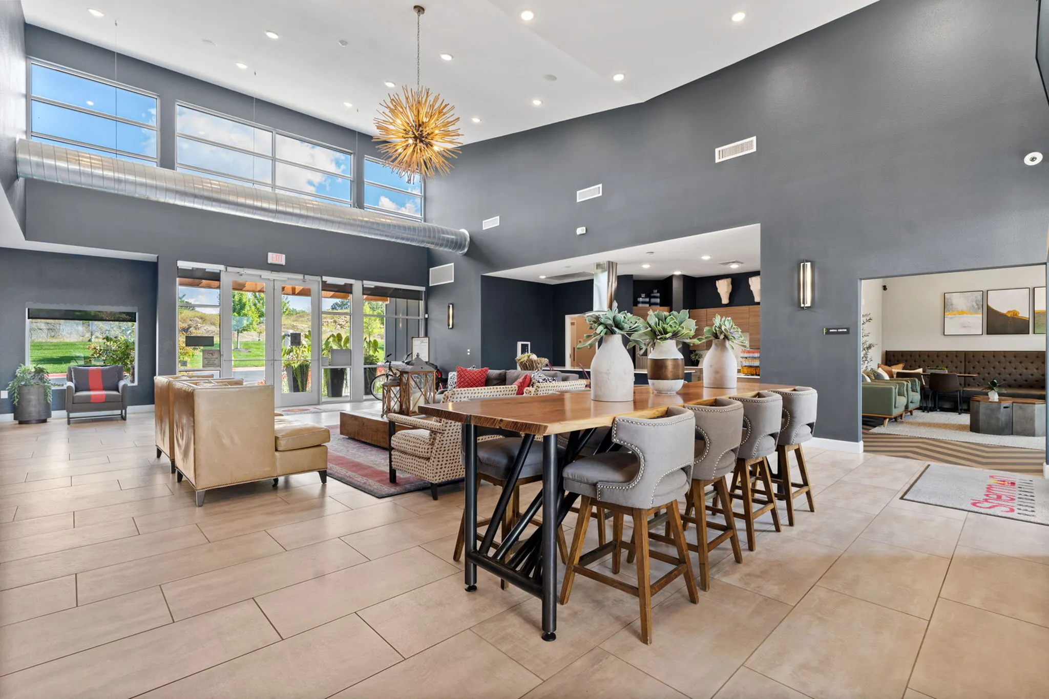 Bright and modern apartment lounge with high ceilings, natural light, chic furniture, and a stylish dining area.