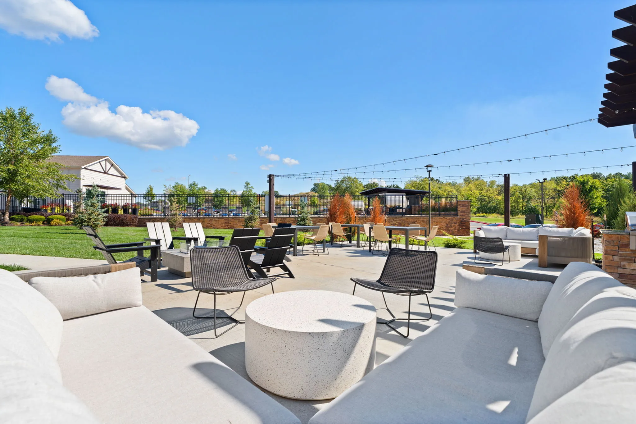 Inviting outdoor lounge area with plush seating, modern decor, and vibrant green lawn on a sunny day, perfect for relaxation and social gatherings.