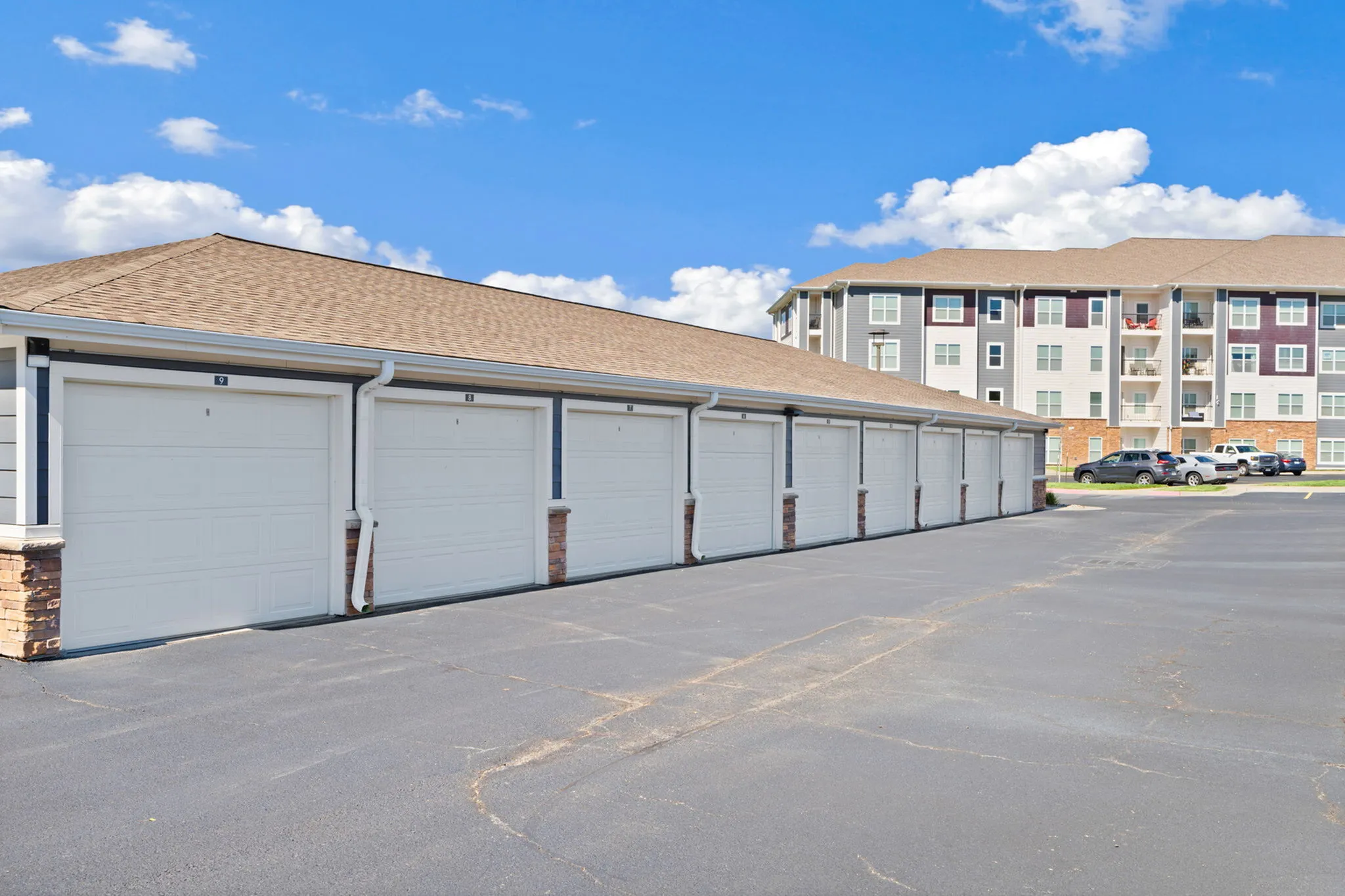 Modern apartment complex with convenient garage parking and spacious balconies, set against a vibrant blue sky.