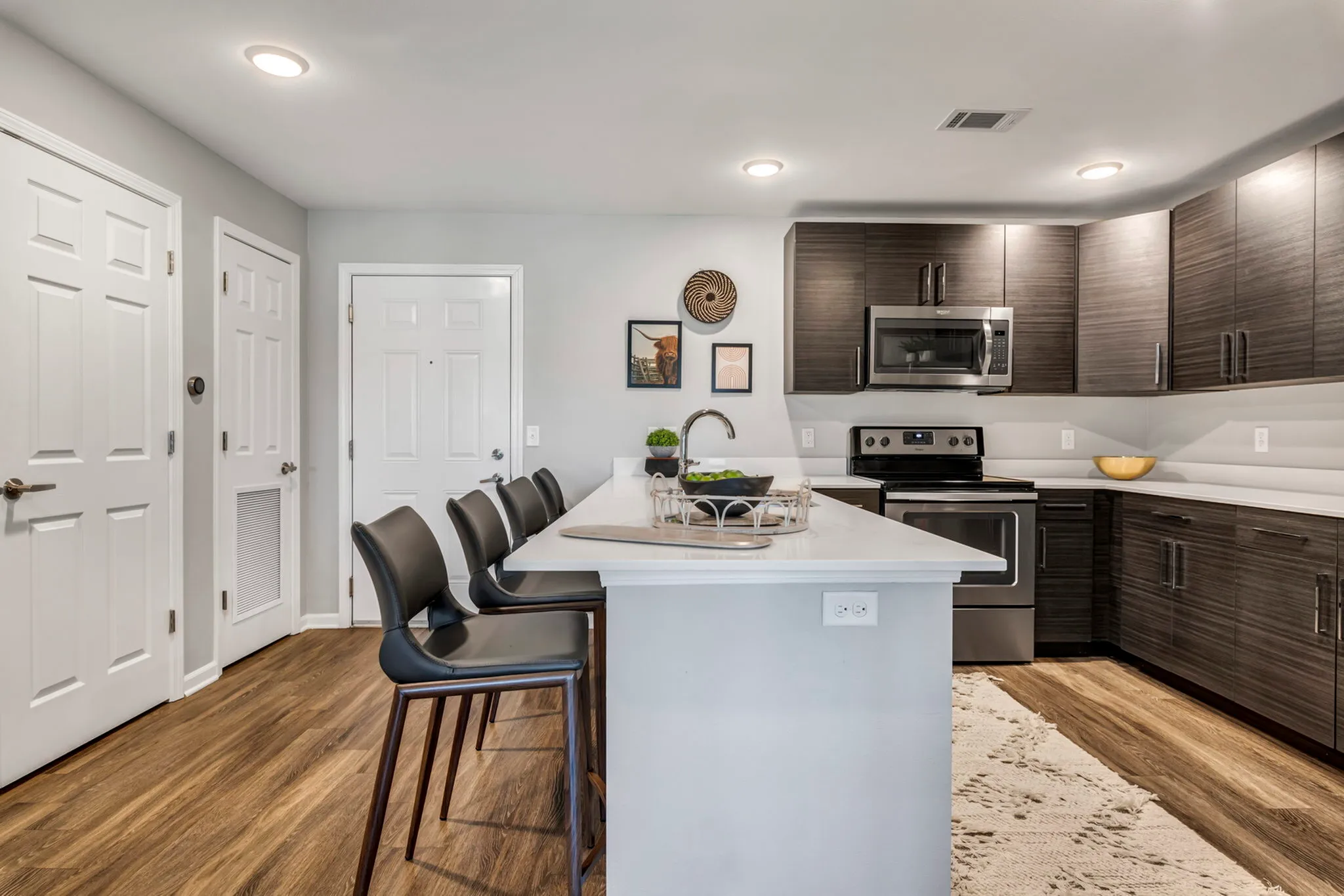 Sleek modern kitchen with dark cabinetry, stainless steel appliances, and a chic breakfast bar featuring stylish seating and elegant decor.