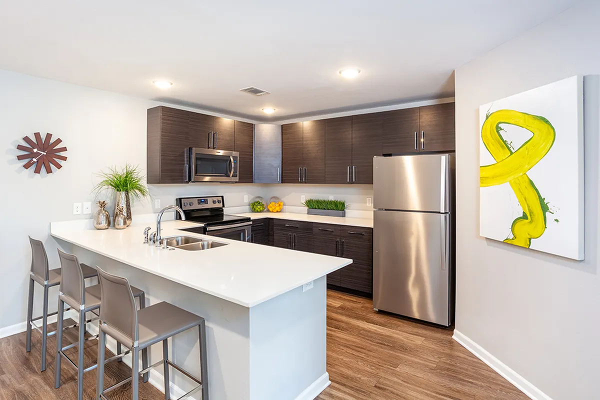Modern kitchen with sleek dark wood cabinets, stainless steel appliances, and a stylish breakfast bar with seating.