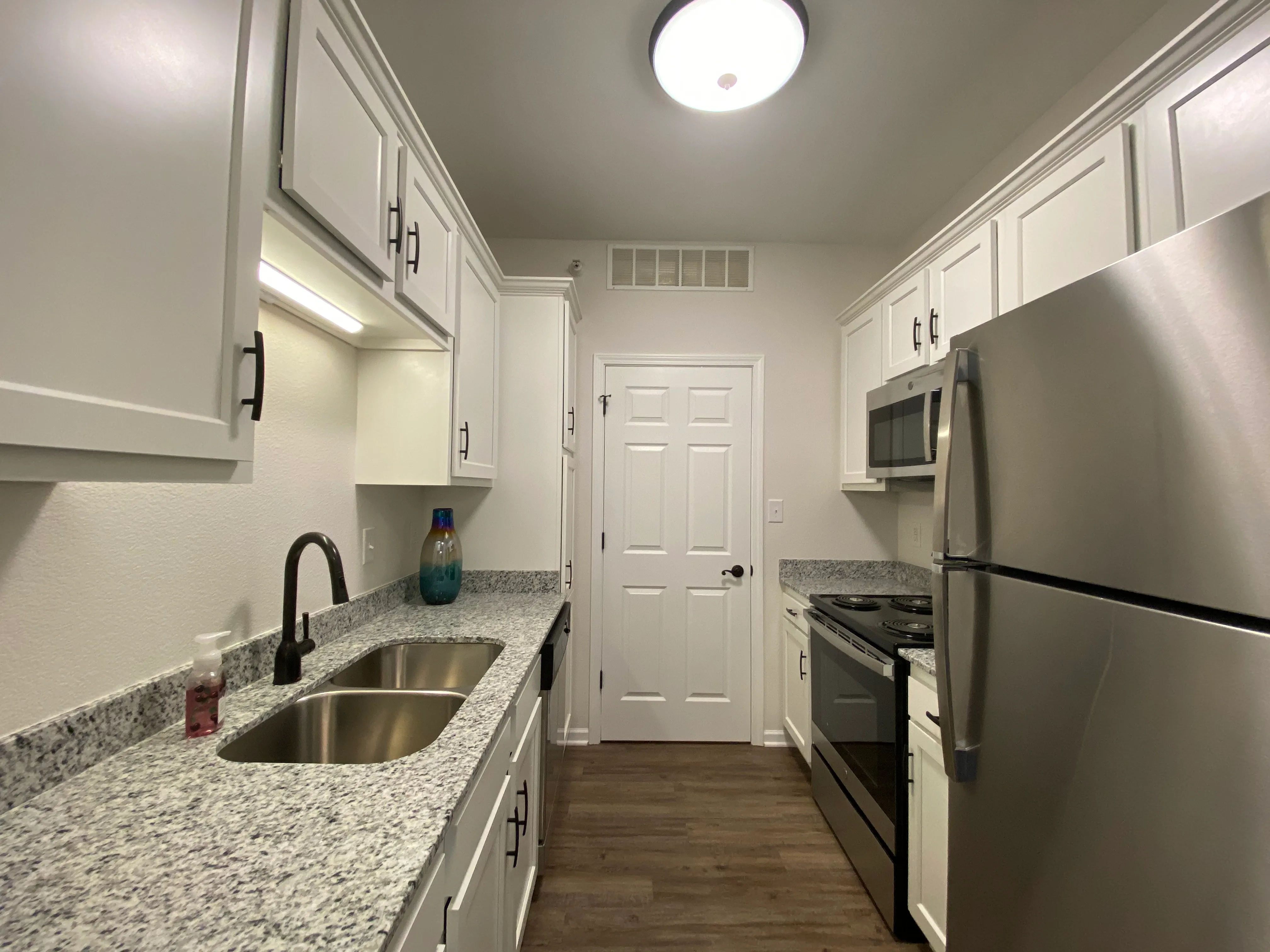 Sleek modern kitchen with granite countertops, stainless steel appliances, and elegant white cabinetry.