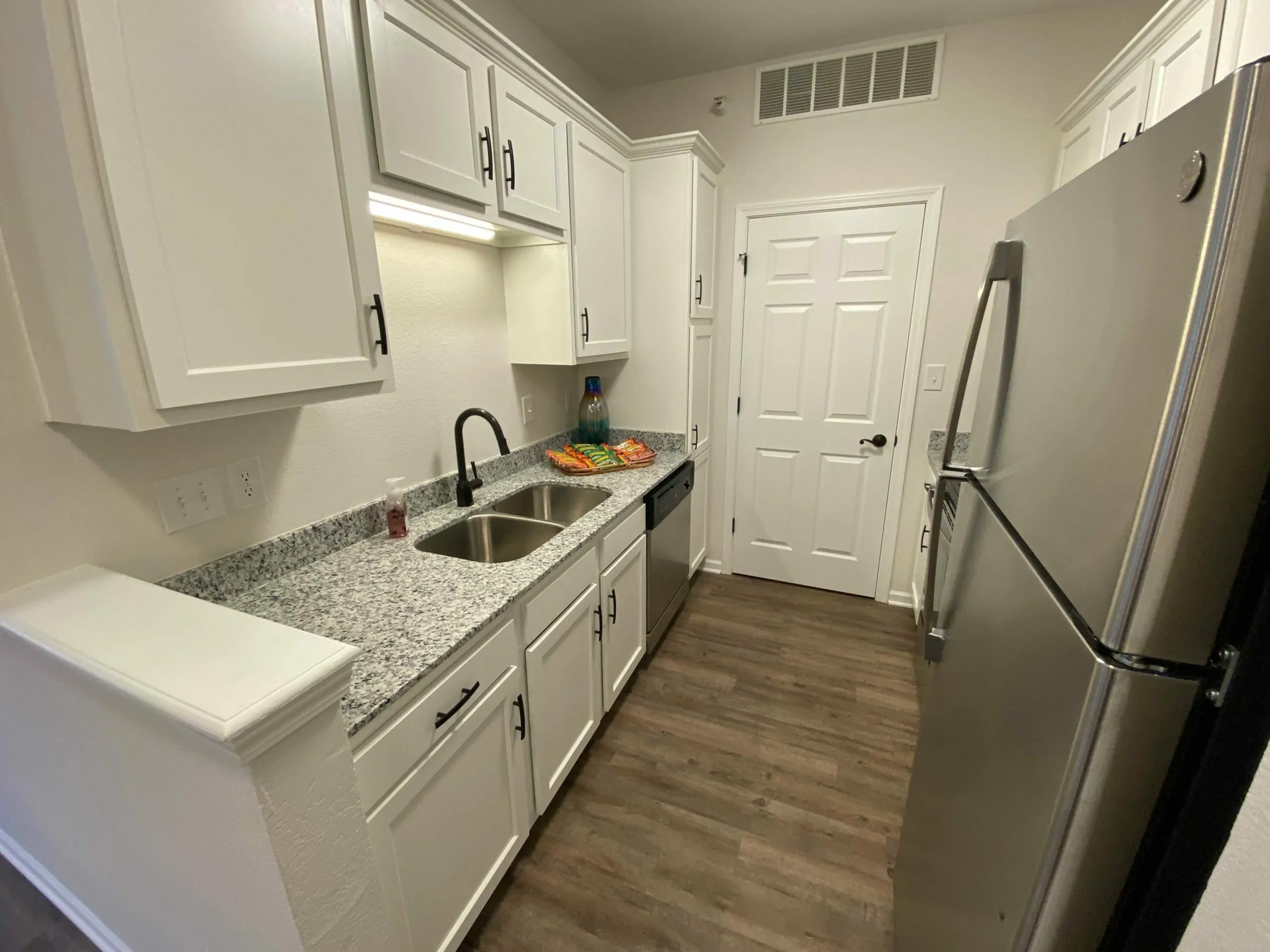Sleek kitchen with modern white cabinets, granite countertops, and stainless steel appliances, offering a blend of elegance and functionality.