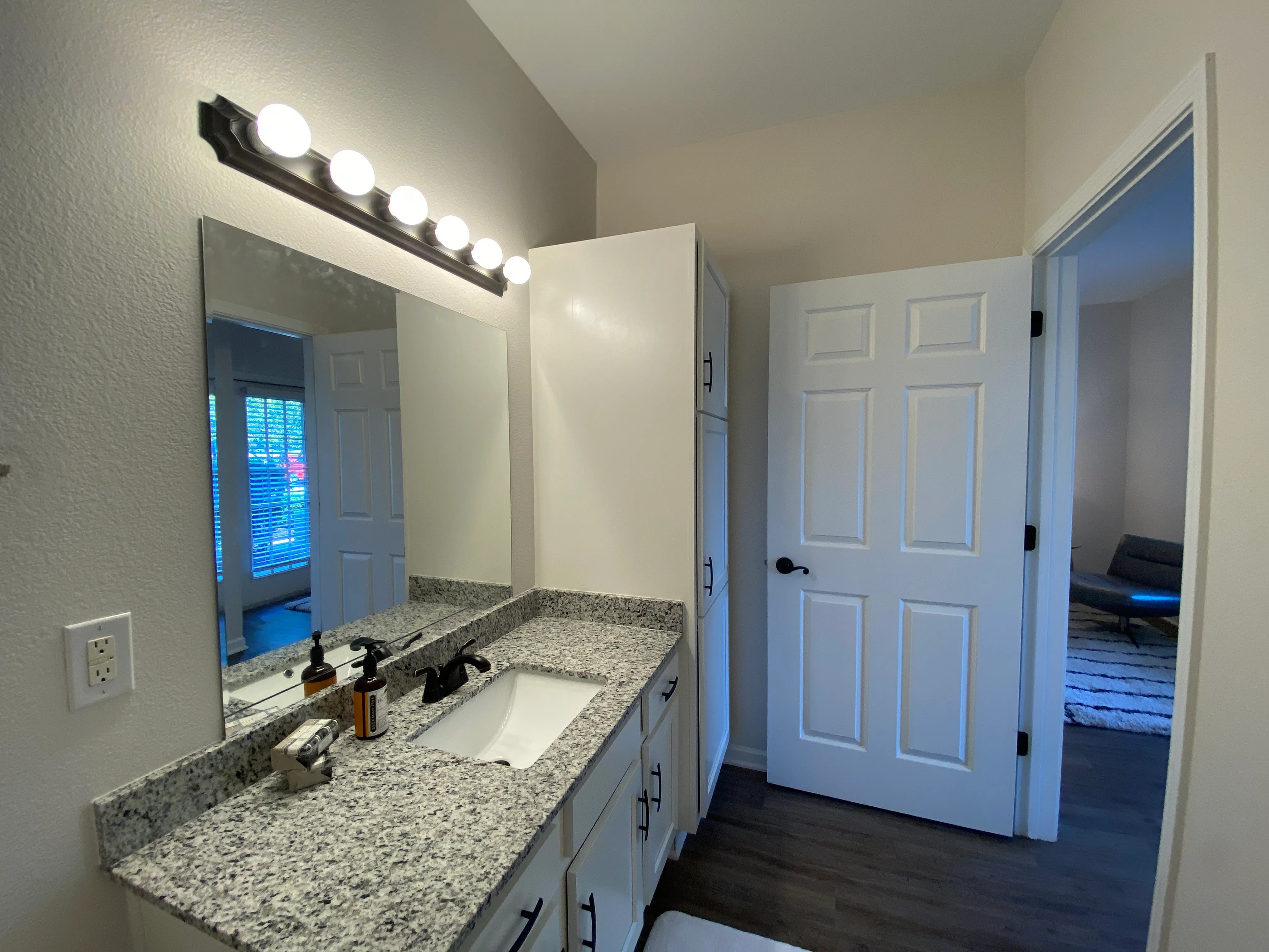 Elegant bathroom featuring a sleek granite countertop, stylish lighting, and modern cabinetry.