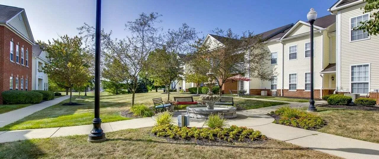 Charming apartment complex courtyard with vibrant landscaping, benches, and a central fountain offering a serene outdoor retreat.
