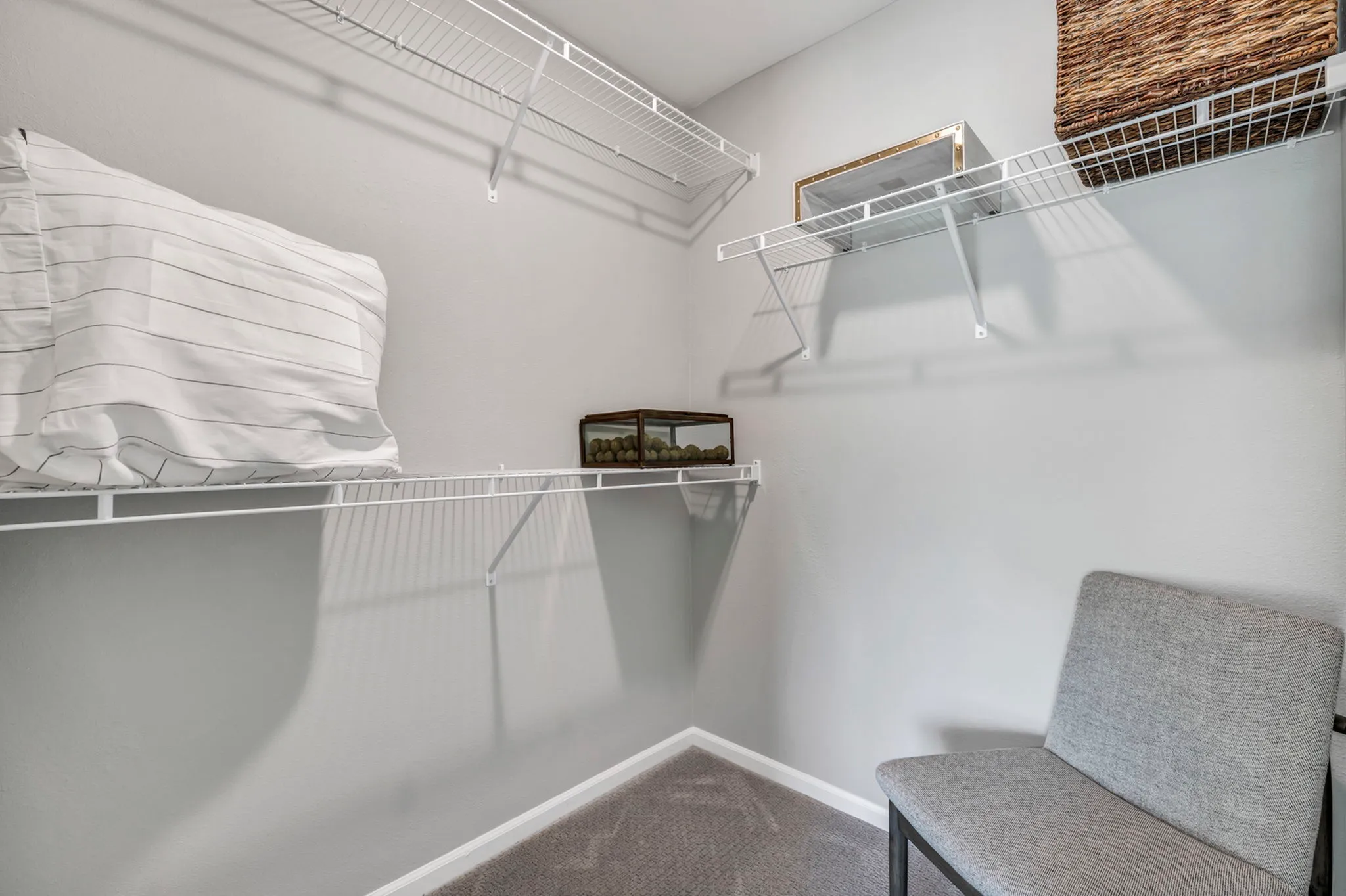 Modern closet space featuring sleek wire shelving, a comfortable gray chair, and organized storage solutions.