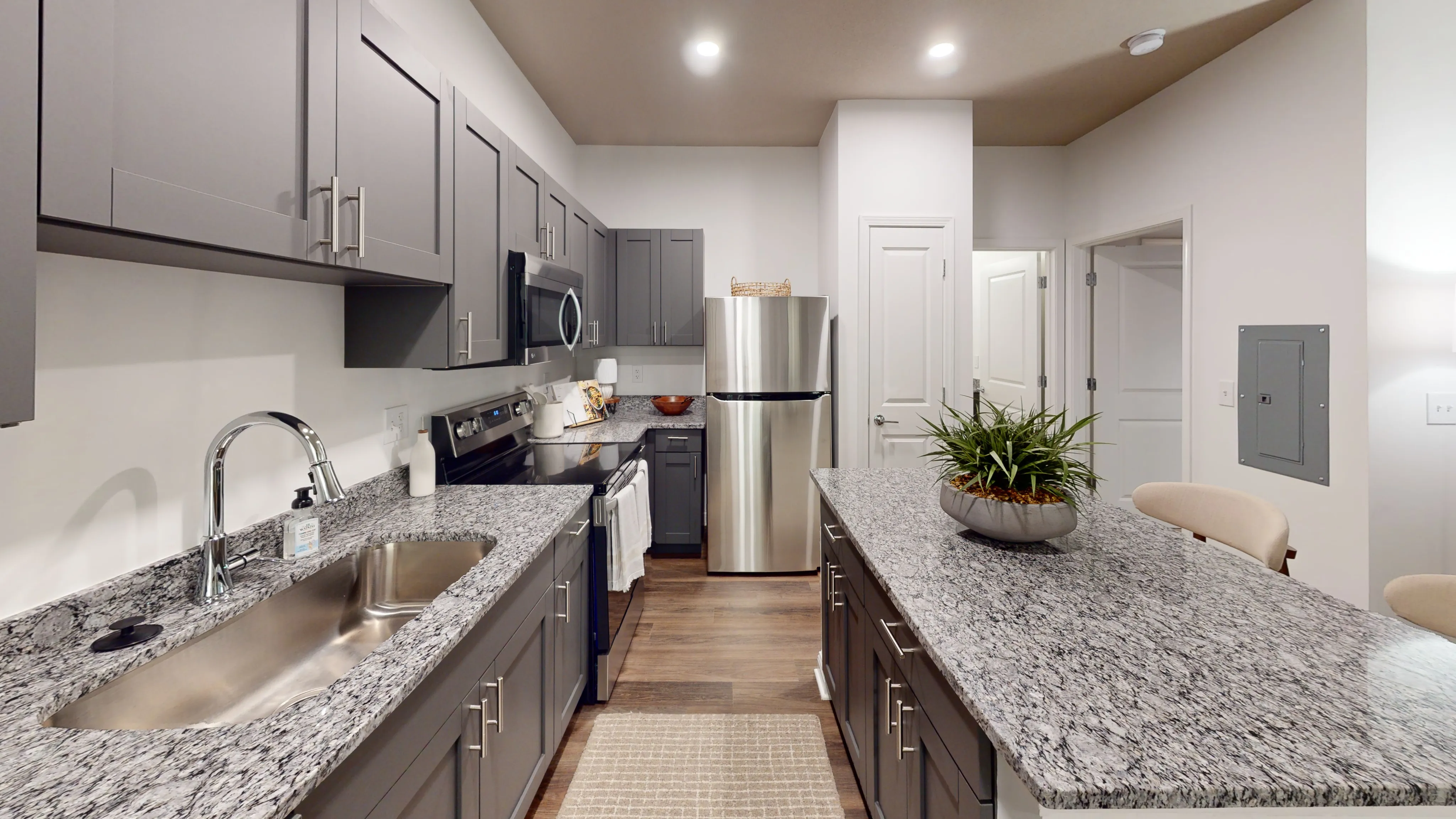 Modern kitchen with sleek gray cabinets, stainless steel appliances, and elegant granite countertops.