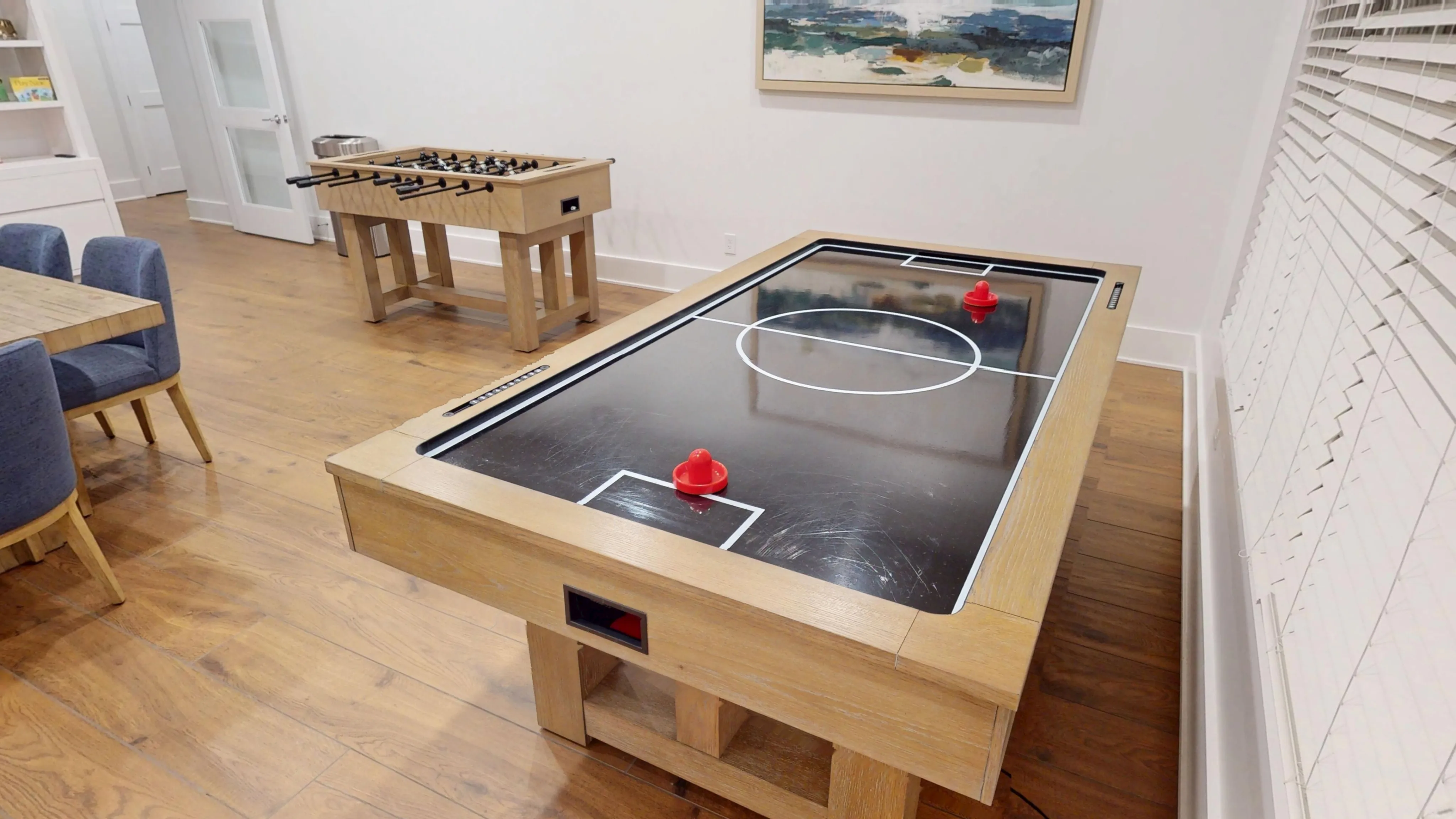 Chic recreation room featuring a sleek air hockey table, a foosball table, and stylish seating for ultimate relaxation.