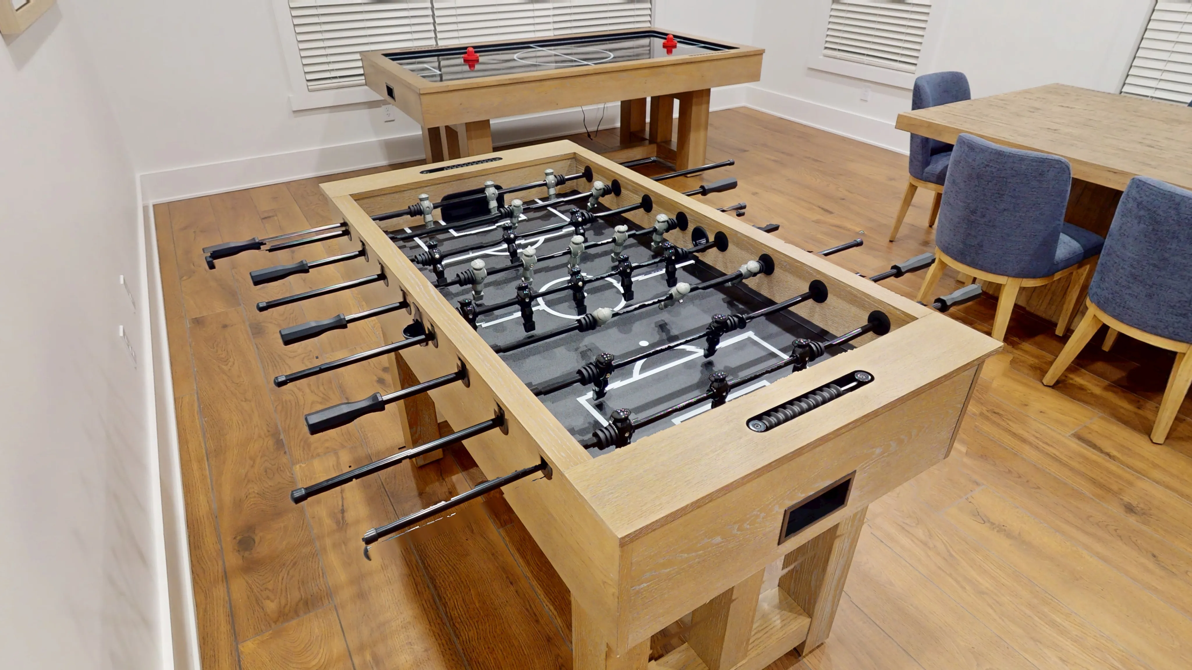 Chic game room featuring a modern foosball table and stylish high-top table with elegant blue chairs, perfect for entertainment and relaxation.