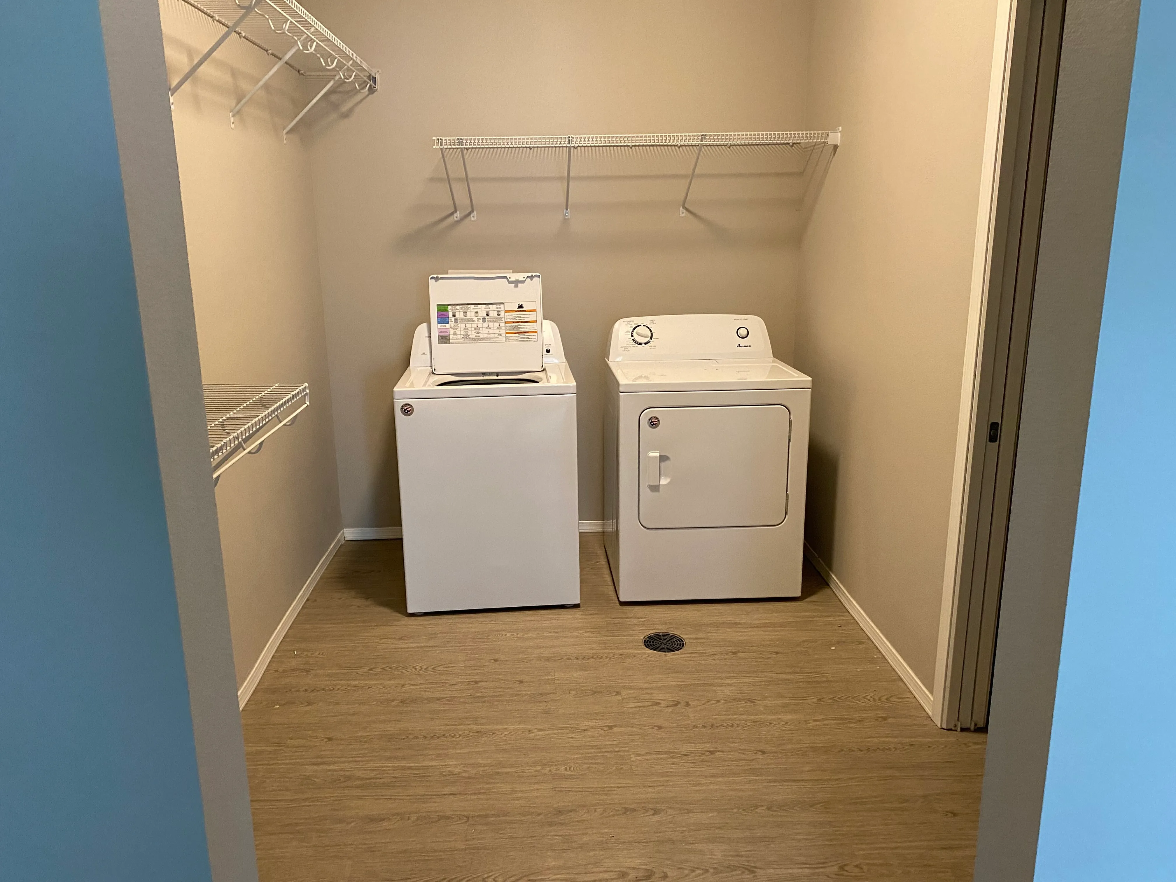 Chic laundry room featuring modern washer and dryer with ample shelving and elegant wood flooring.