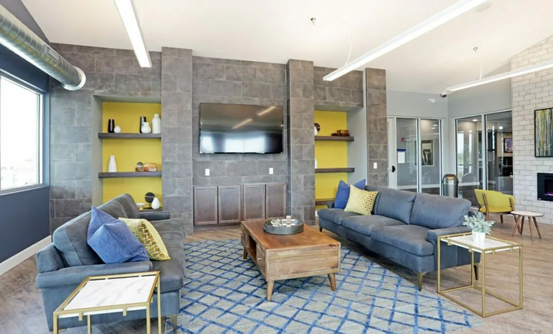 Modern living room with chic grey sofas, vibrant yellow accents, and a sleek wall-mounted TV, perfect for relaxation and entertainment.