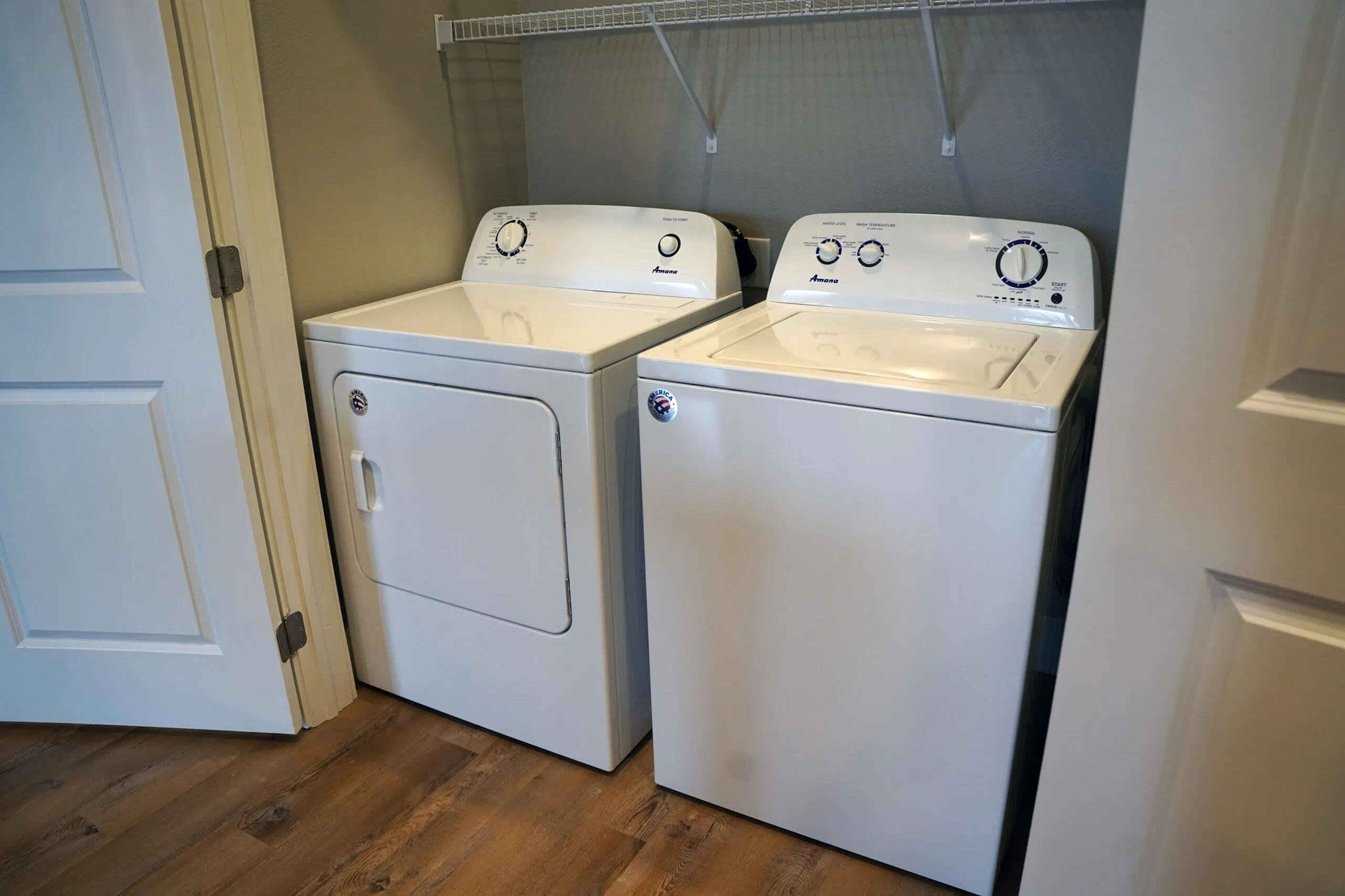 Modern laundry area featuring a sleek washer and dryer in a well-lit space with wooden flooring and neutral tones.