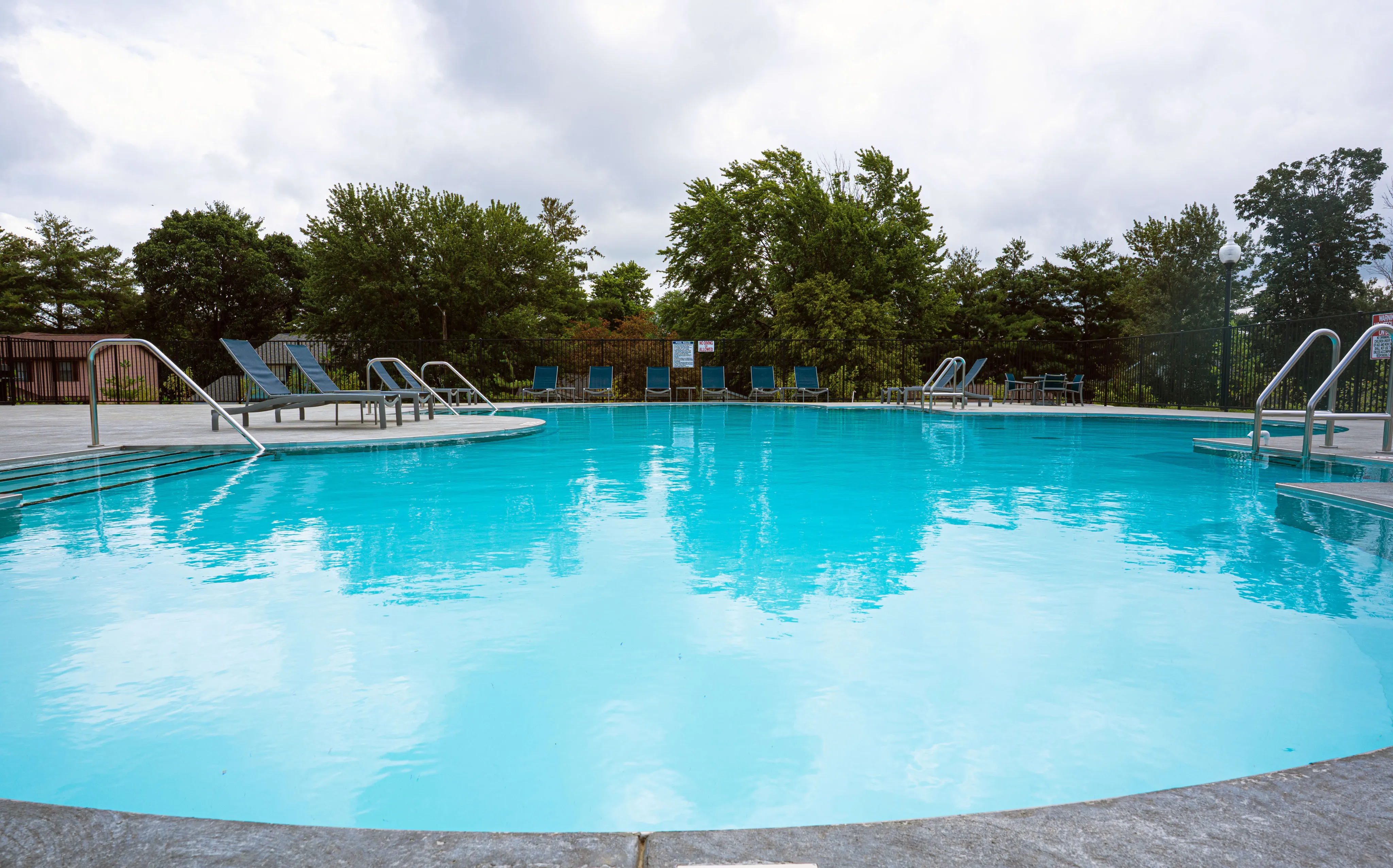 Serene outdoor pool area with inviting lounge chairs and lush green surroundings, perfect for relaxation and leisure.