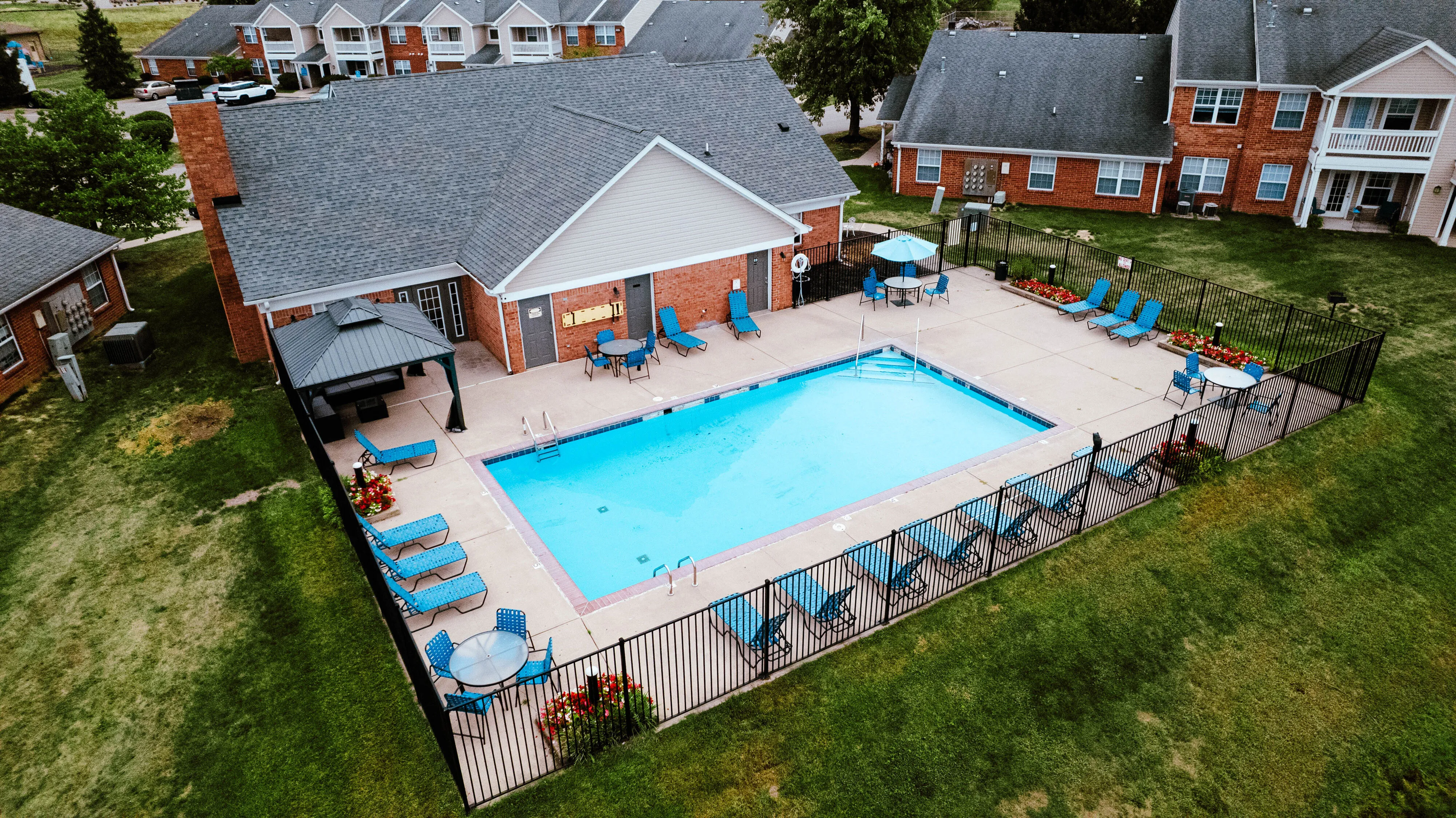 Charming apartment complex featuring a pristine outdoor pool surrounded by inviting lounge chairs and vibrant landscaped gardens.