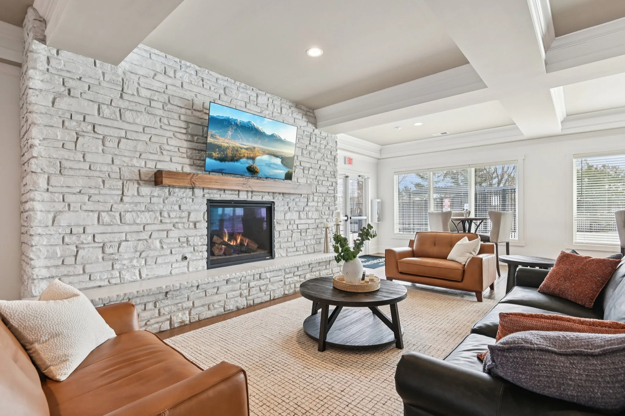 Inviting living room with a cozy fireplace, stylish stone accent wall, and plush leather seating. Vibrant natural light floods the space, creating a warm and welcoming atmosphere perfect for relaxation.