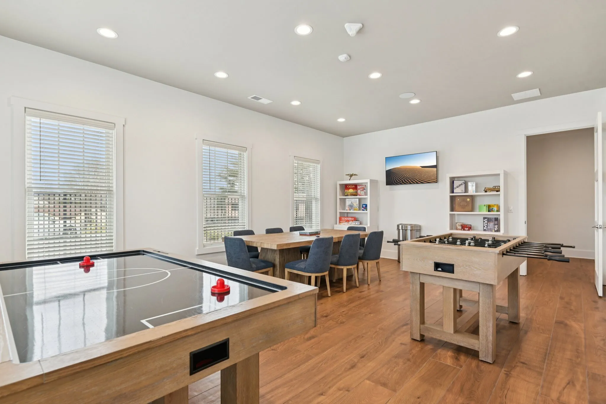 Bright and inviting game room featuring a foosball table, air hockey, and a cozy seating area with board games.