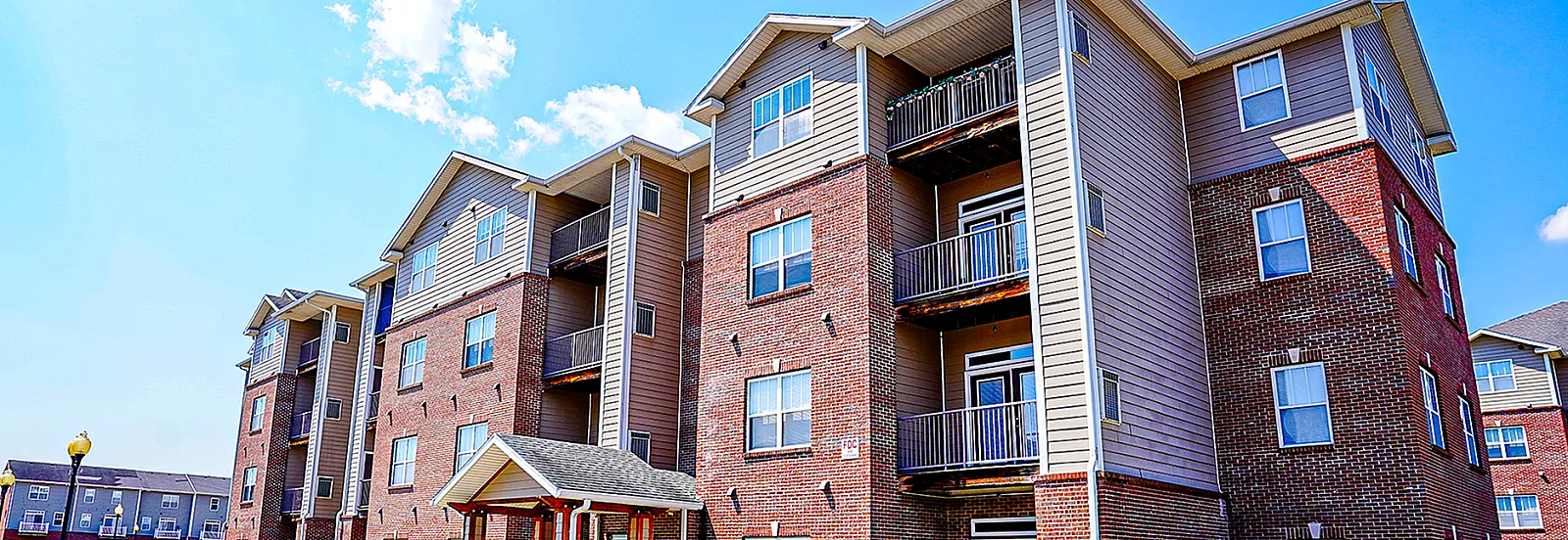 Charming modern apartment building with spacious balconies set against a clear blue sky, offering scenic views and ample natural light.