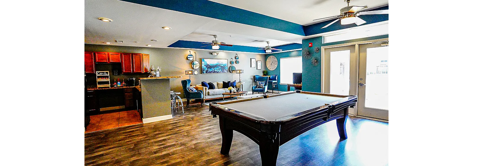 Chic entertainment room with stylish decor, featuring a pool table, cozy seating area, and modern kitchenette.