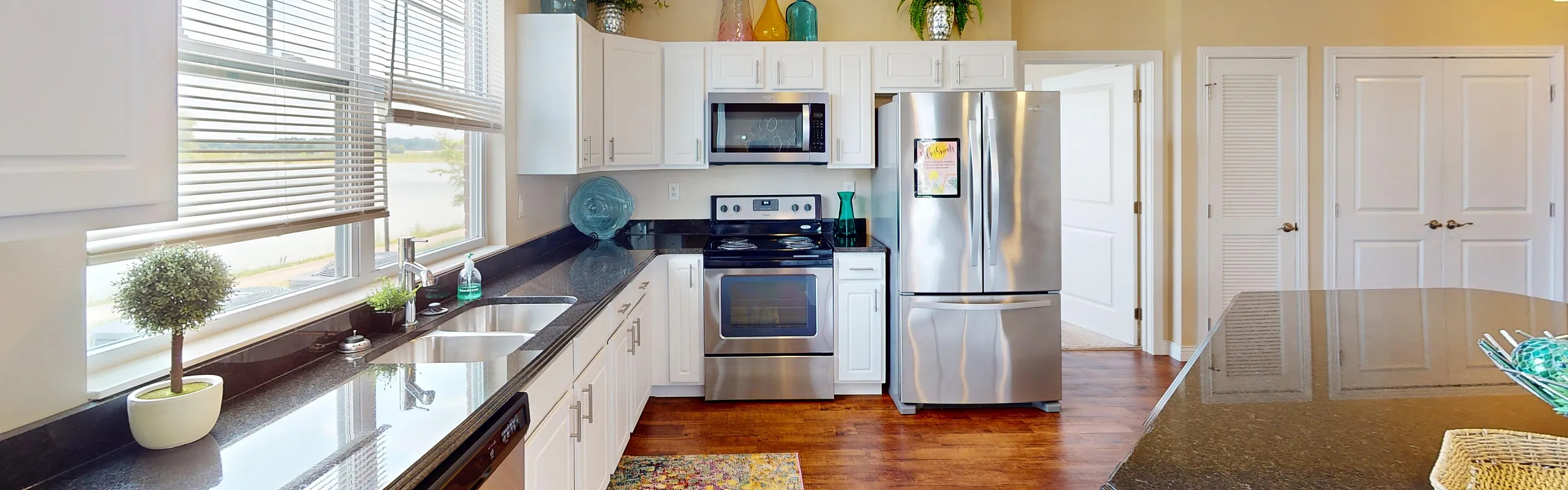 Bright and modern kitchen with stainless steel appliances, sleek granite countertops, and stylish white cabinetry.