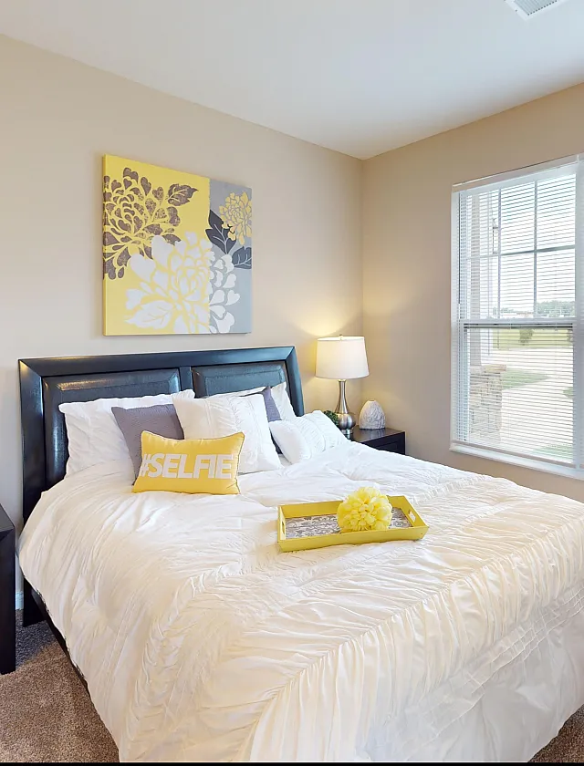 Bright and inviting bedroom featuring a plush bed, stylish decor, and large windows allowing natural light to flood the space.