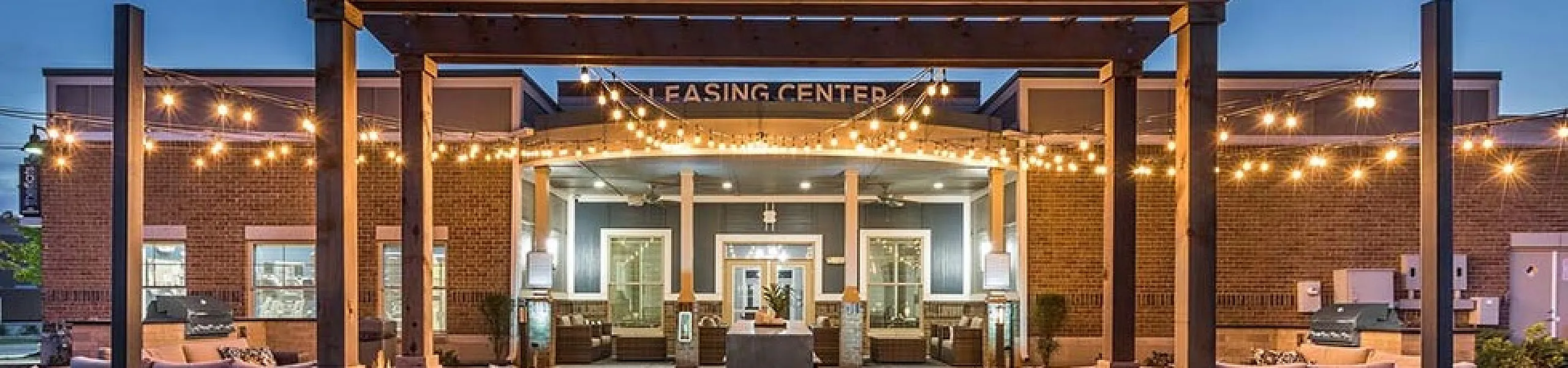 Elegant leasing center entrance with ambient string lighting and cozy outdoor seating.