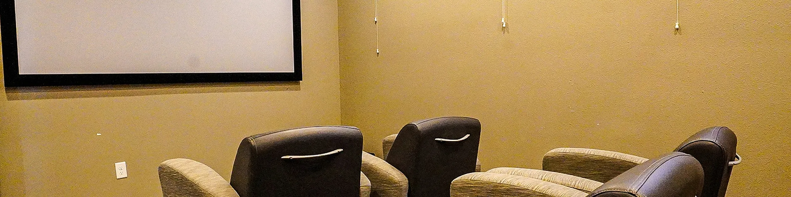 Cozy home theater room with plush seating and a large screen for an immersive entertainment experience.